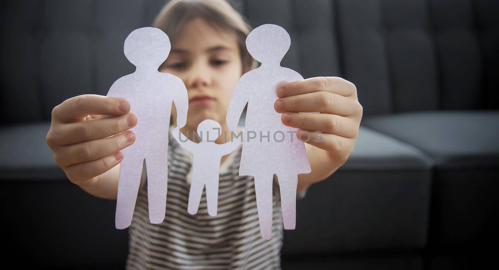 Child with a paper family in his hands. the concept of divorce, custody and child abuse. Selective focus. by yanadjana