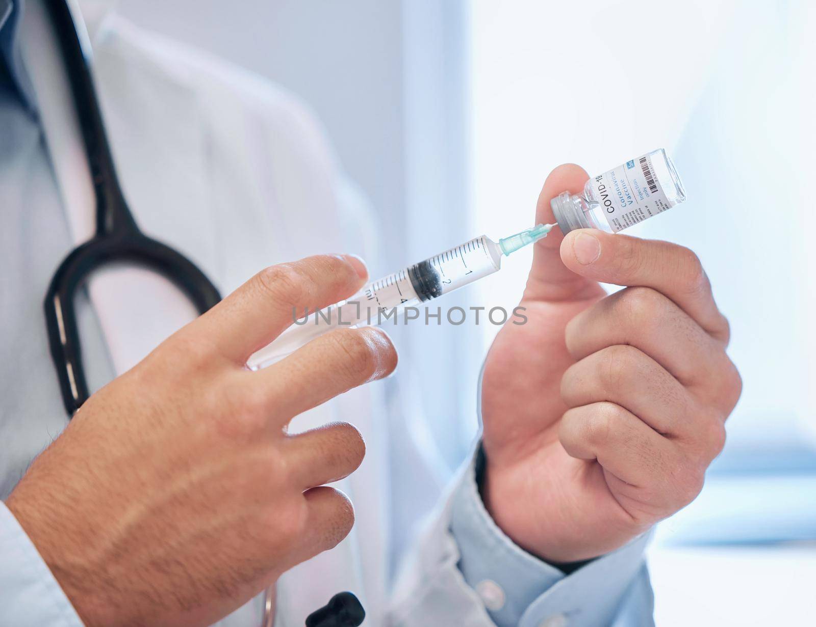 Shot of a dentist filling a needle with covid vaccine.