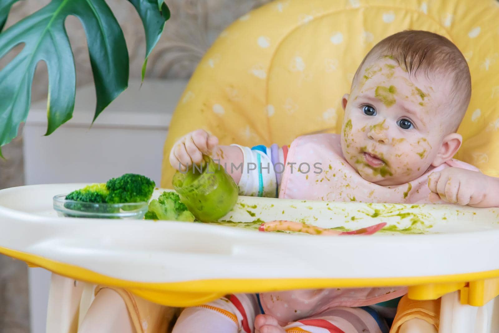 Little baby eats broccoli puree himself. Selective focus. People.