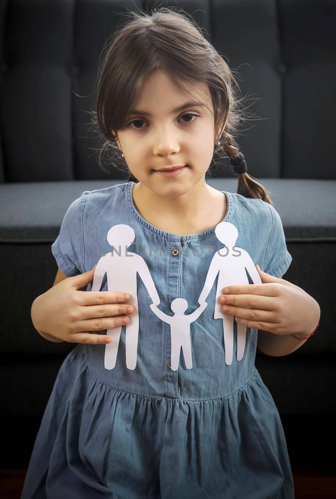 Child with a paper family in his hands. the concept of divorce, custody and child abuse. Selective focus. People.