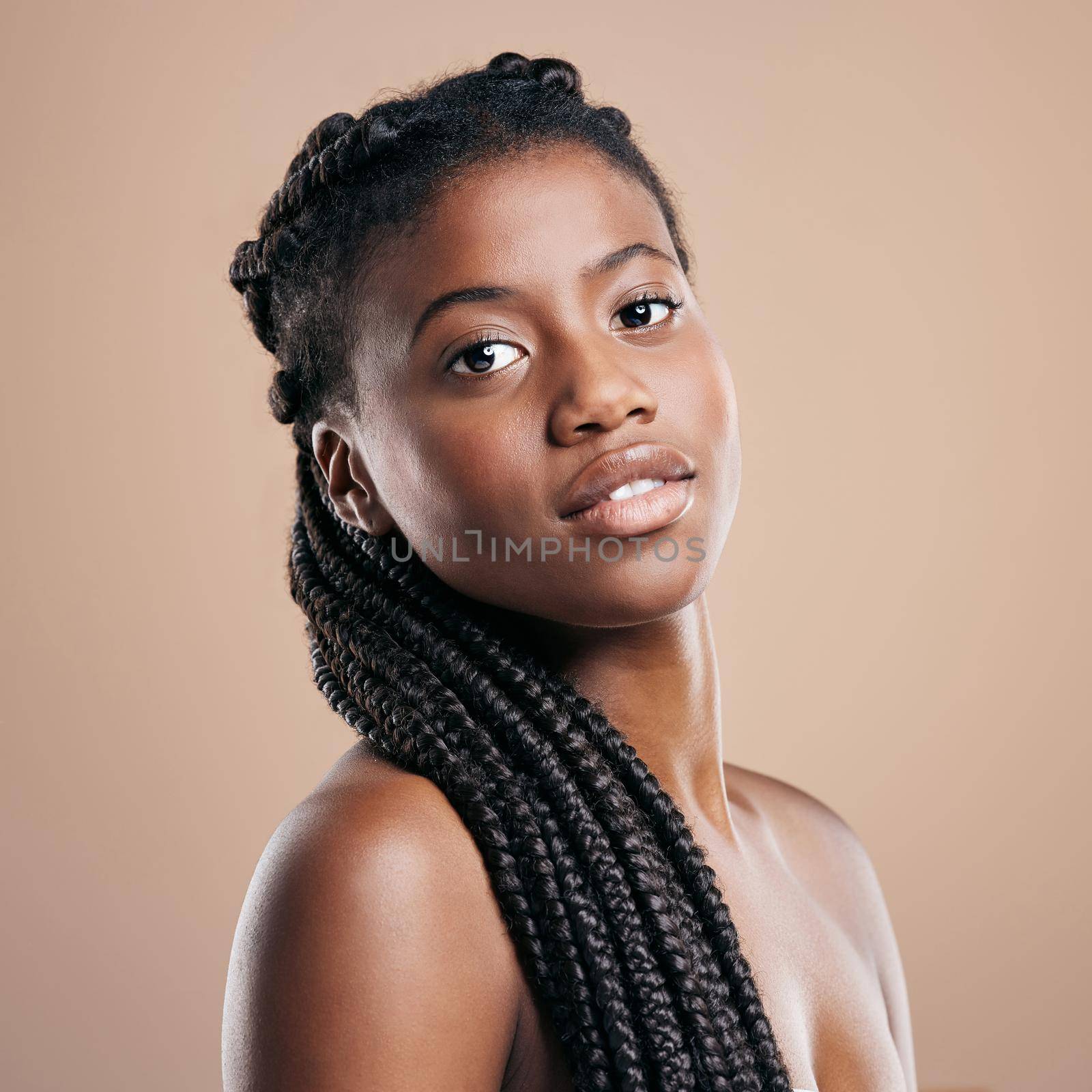My braids are my crown. Cropped portrait of an attractive young woman posing in studio against a brown background. by YuriArcurs