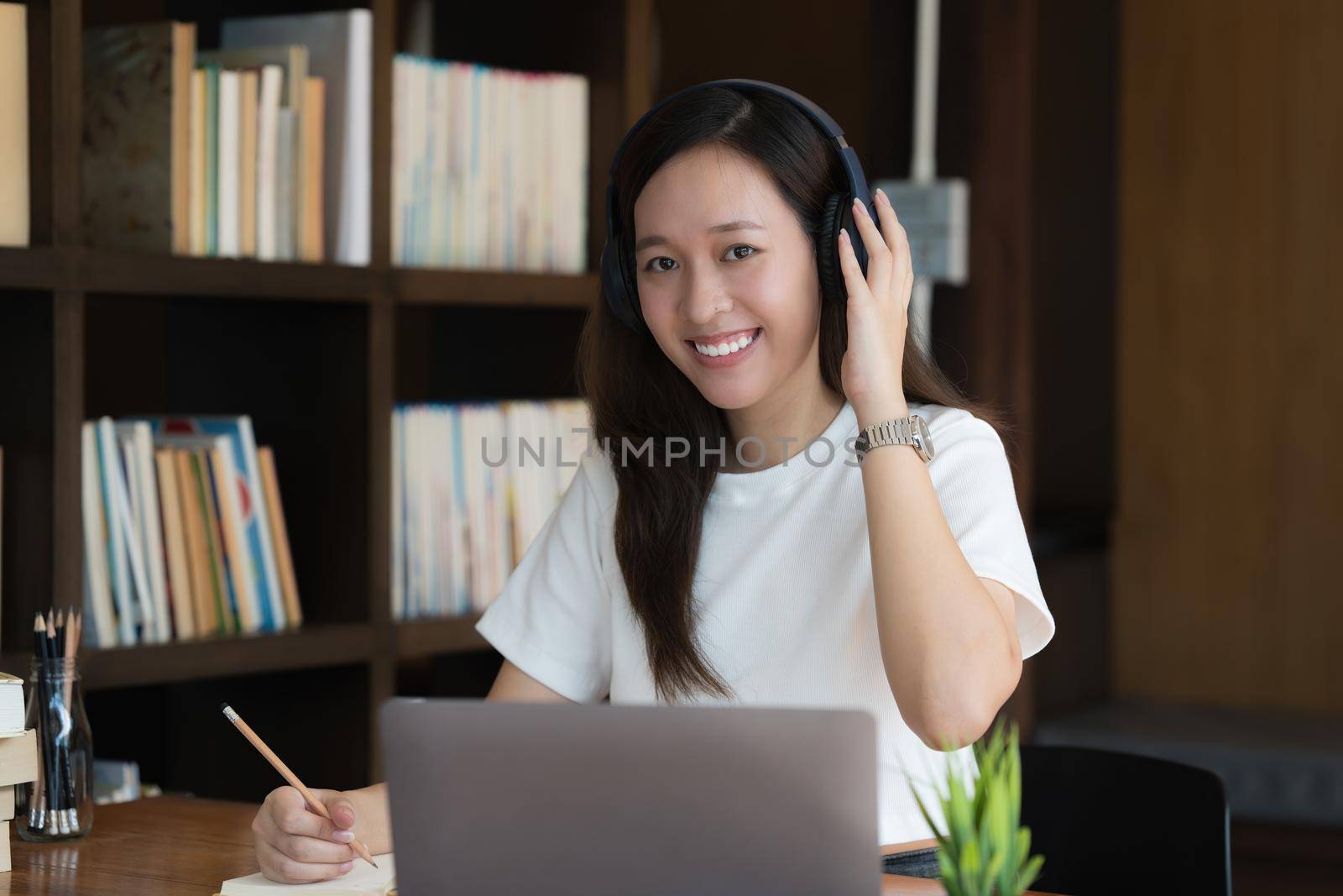 Image of Young woman with a headset working online on laptop computer. studying or working from home online concept