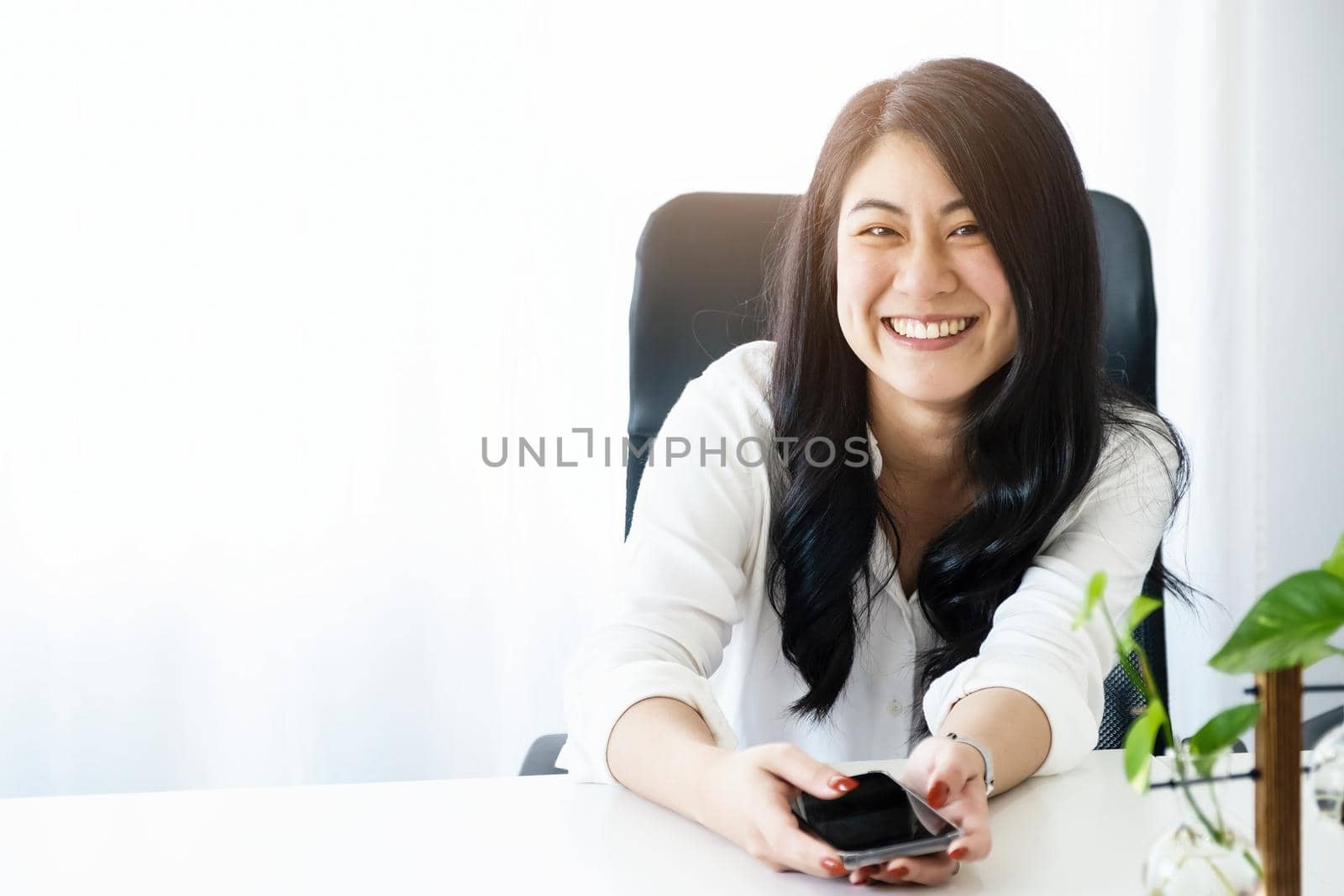 Portrait of a young Asian woman smiling happily while taking a break after work by Manastrong