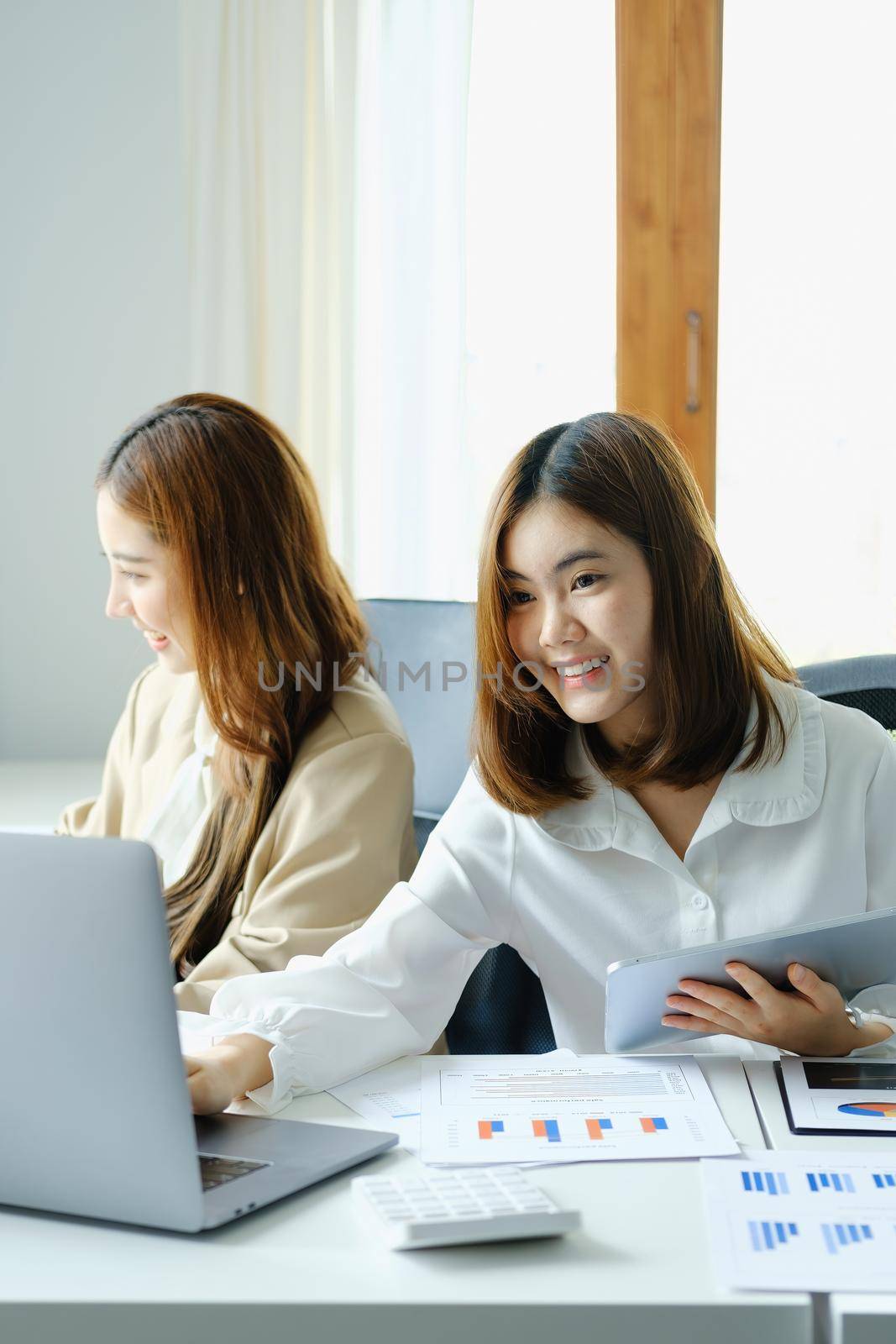 Negotiation, Analysis, Discussion, Portrait of an Asian woman economist and marketer using computer laptop to plan investments and financial to prevent risks and losses for the company.