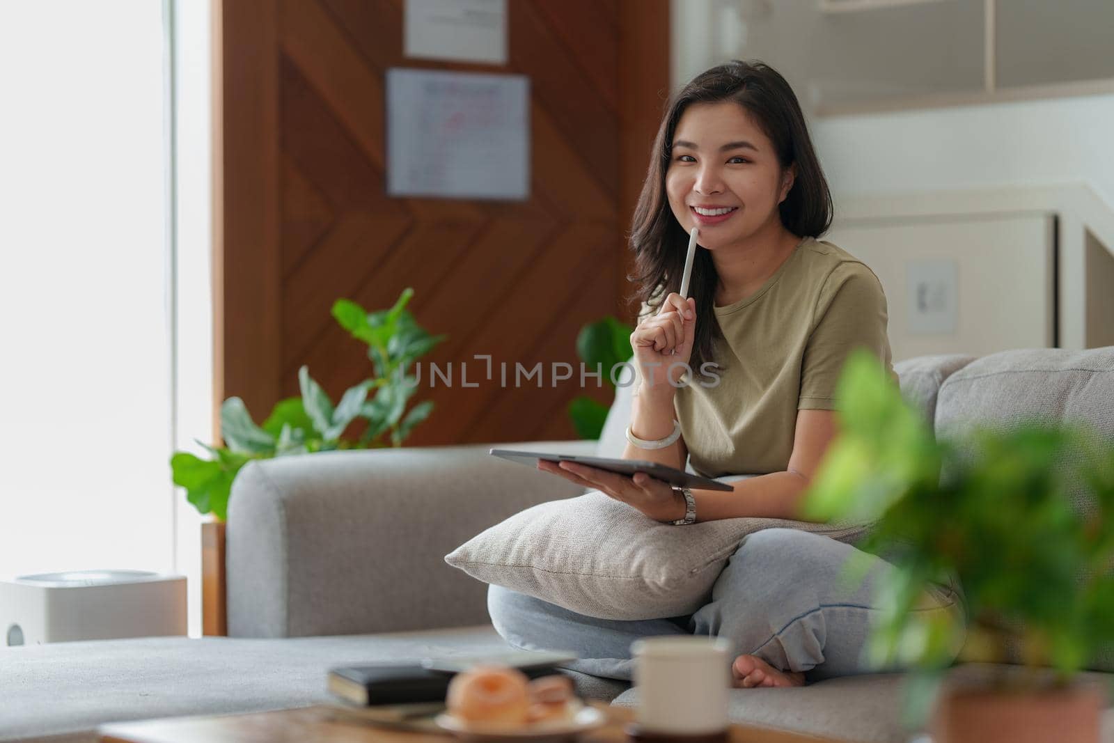 Portrait of Young Asian woman using social media for chatting by digital tablet. Lifestyle ,Shopping online, relax on sofa