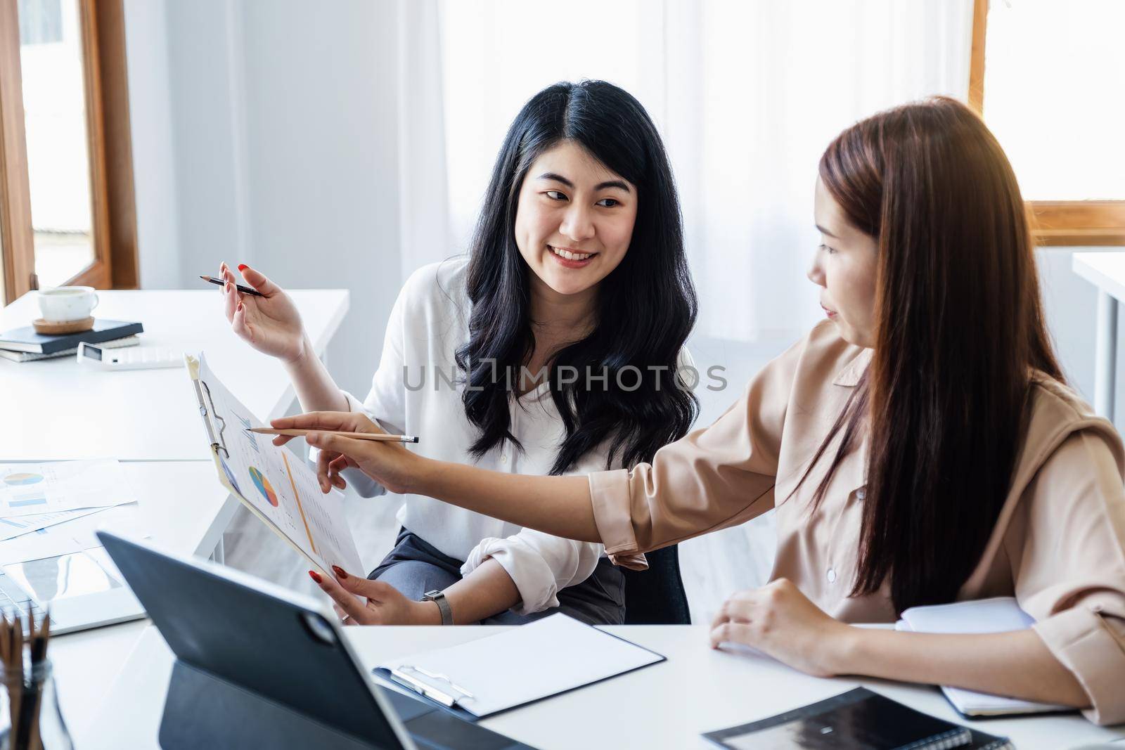 Negotiation, Analysis, Discussion: Portrait of an Asian woman economist and marketer pointing to a financial data sheet to plan investments to prevent risks and losses for the company.