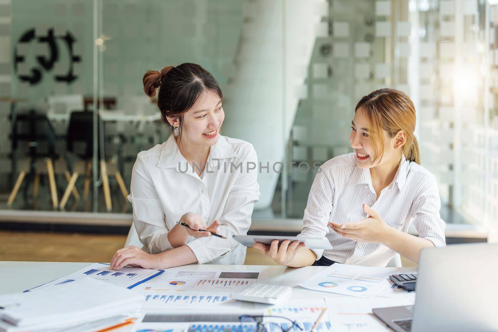 Negotiation, Analysis, Discussion, Portrait of an Asian women economist and marketer using tablet computer to plan investments and financial to prevent risks and losses for the company.