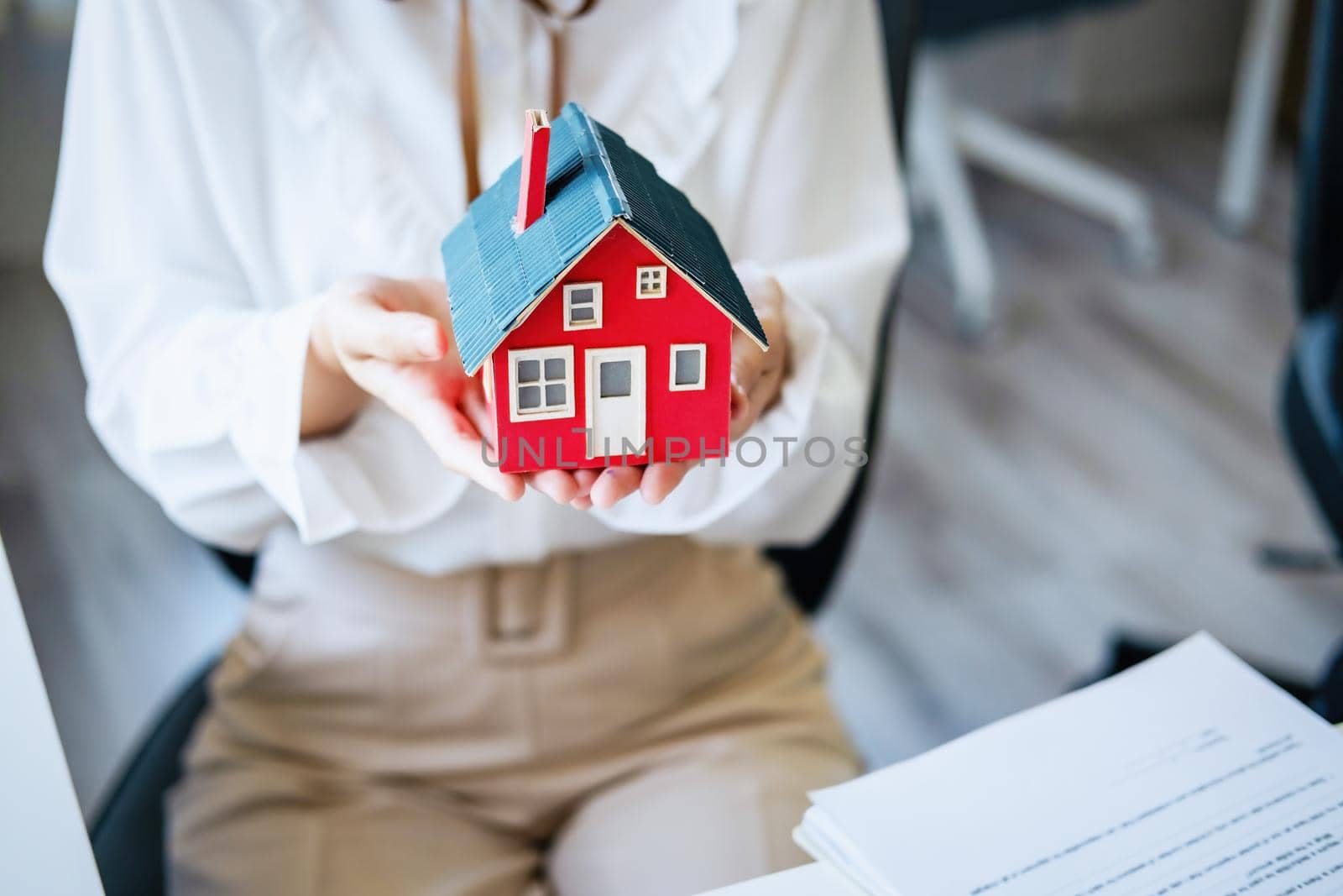 Accountant, businessman, real estate agent, Asian business woman handing model house to customers along with house interest calculation documents for customers to sign. by Manastrong