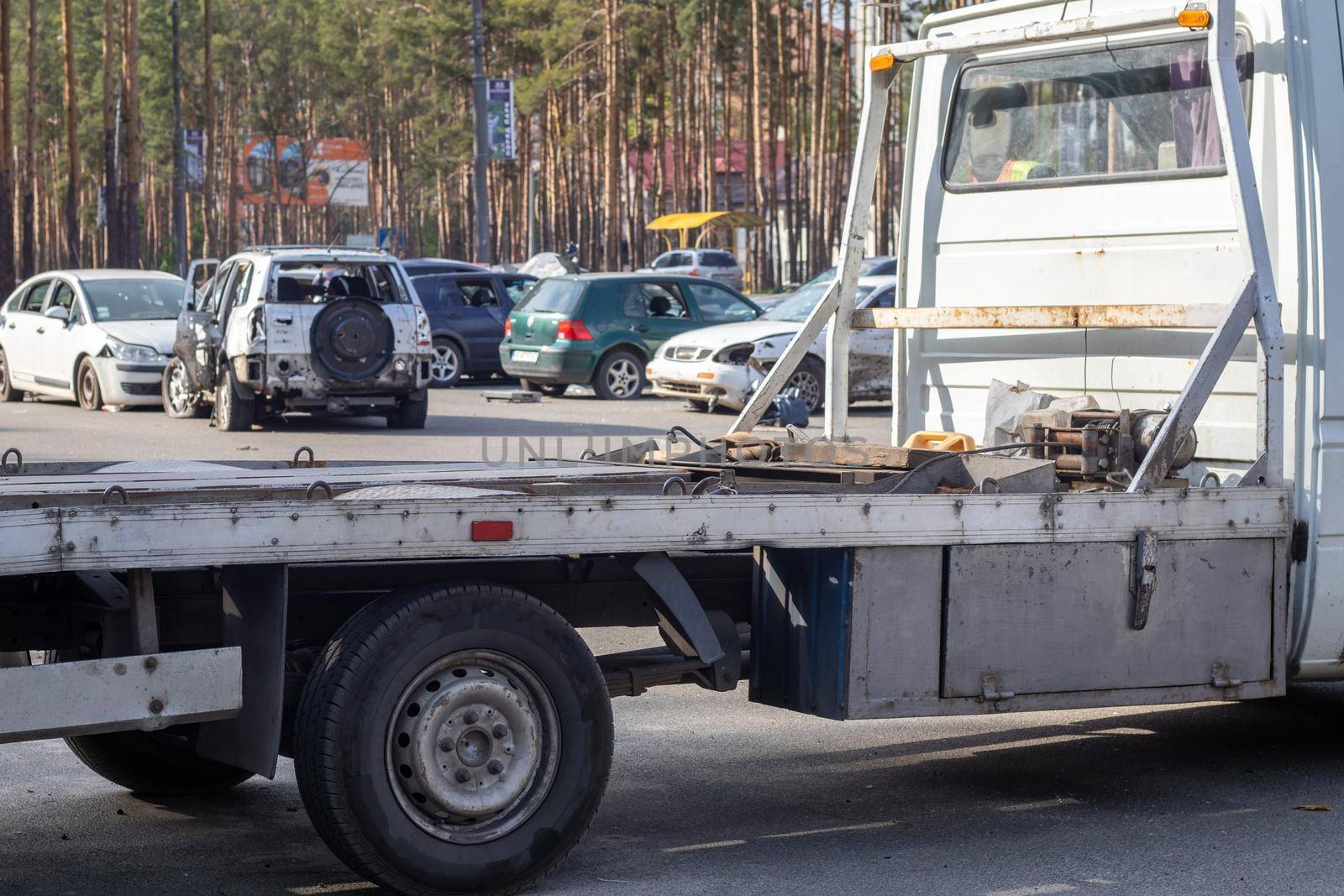 Lots of old cars ready for recycling. Car removal by tow truck. The car is getting ready to be loaded onto a tow truck. Old wrecked cars in a junkyard are waiting to be destroyed in a recycling park
