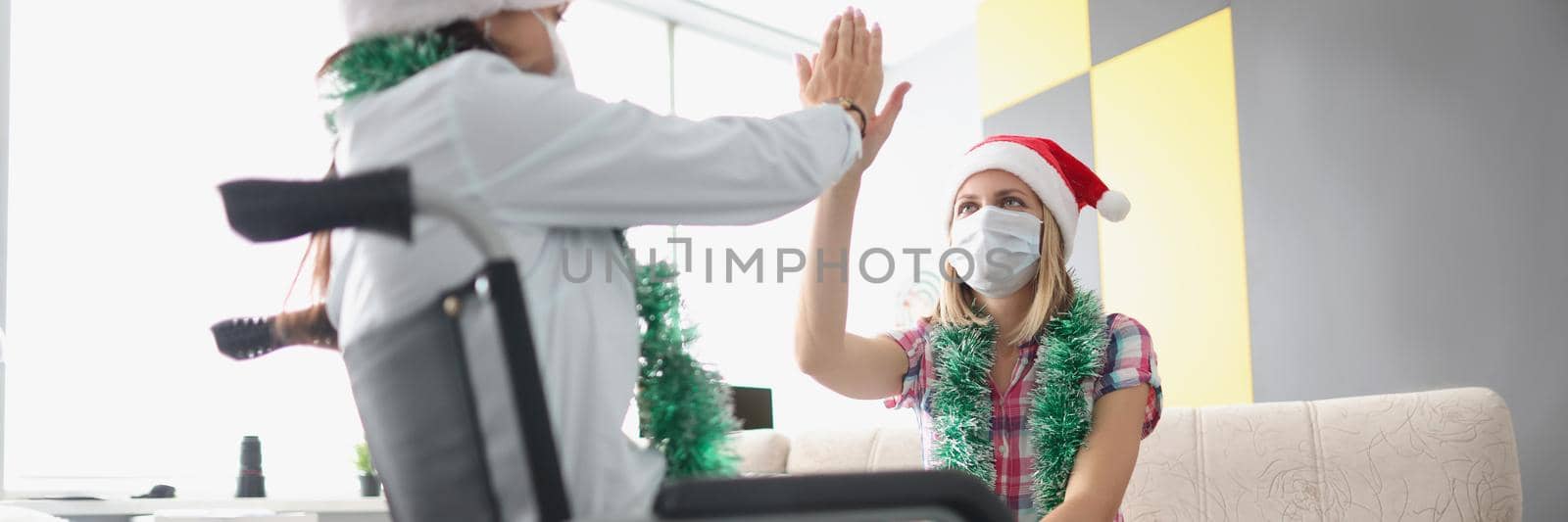 Portrait of female visiting sister in clinic, relative sitting in wheelchair, giving high five. Nursing house, medicine, disabled people, new year concept