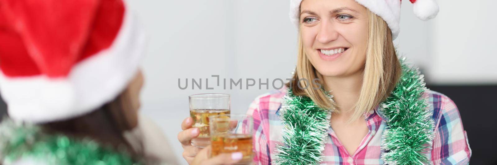 Portrait of happy women celebrate new year, drink alcoholic beverage, wearing festive hats. Joyful atmosphere, time to party. Holiday, home party concept