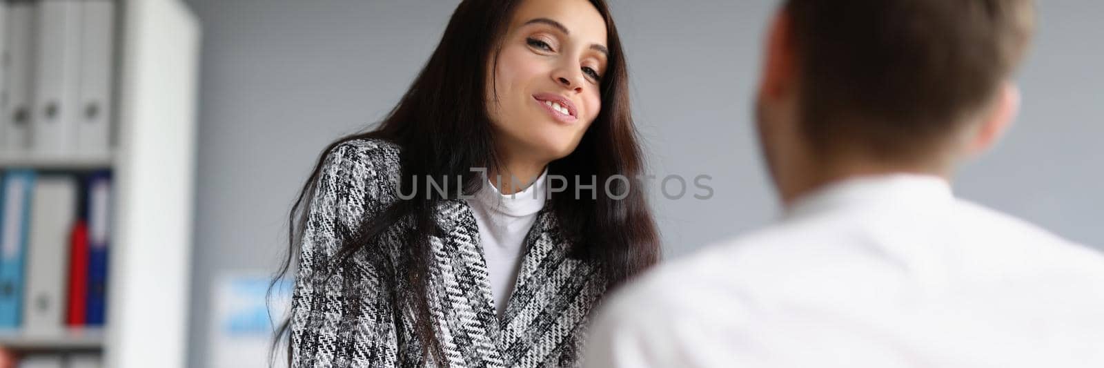 Portrait of beautiful woman in presentable suit talking to male worker on her office. Female boss flirt or explain further work plan. Business, job concept