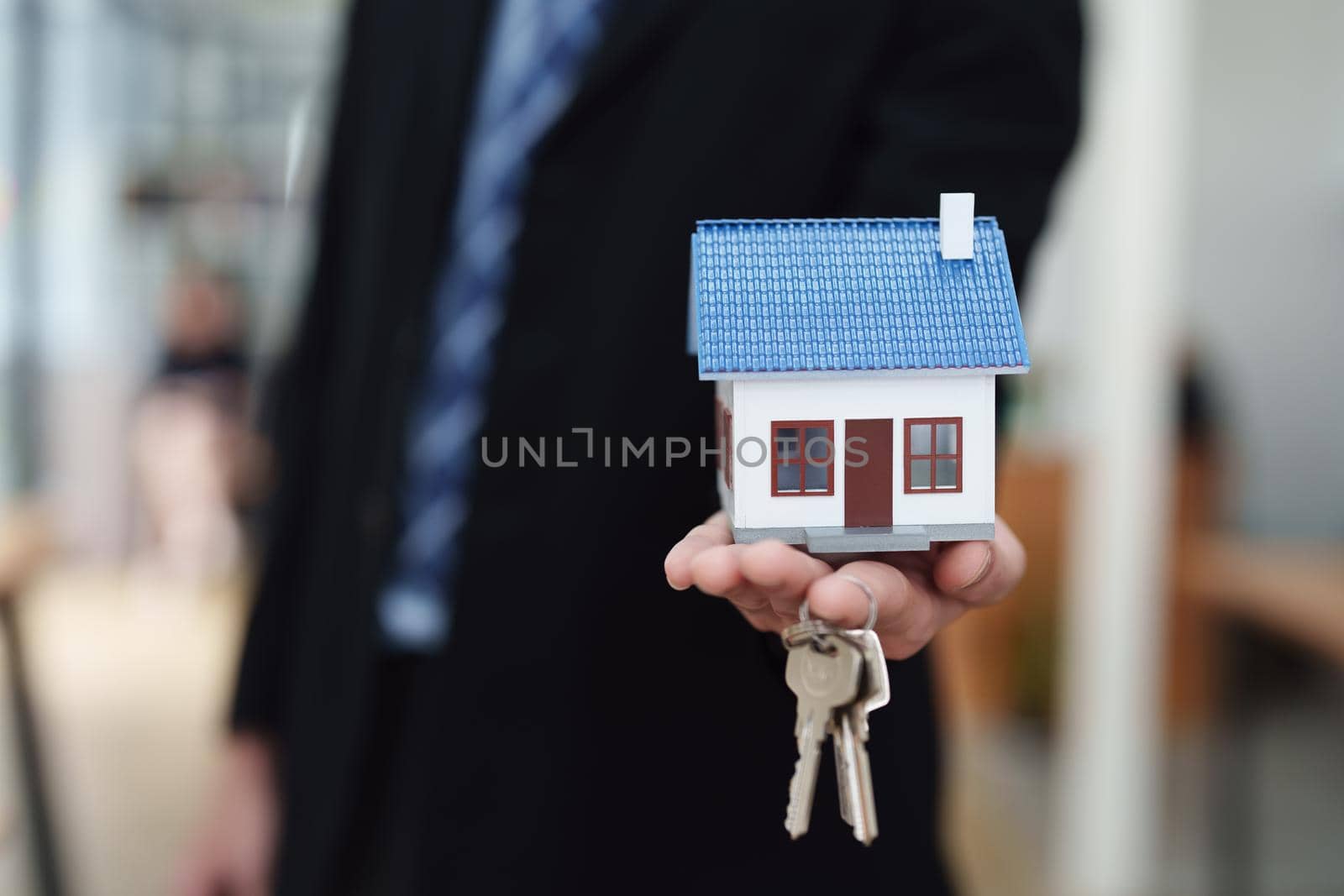 Accountant, businessman, real estate agent, Asian business man handing model house and keys to customers along with house interest calculation documents for customers to sign.