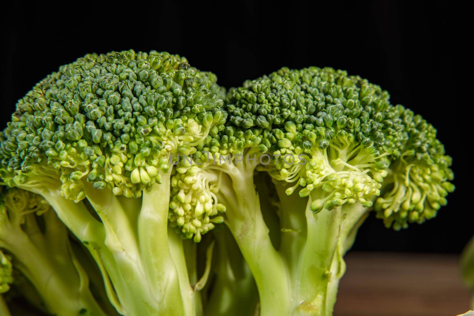 Raw green broccoli florets on a wooden board with ingredients. Close-up.