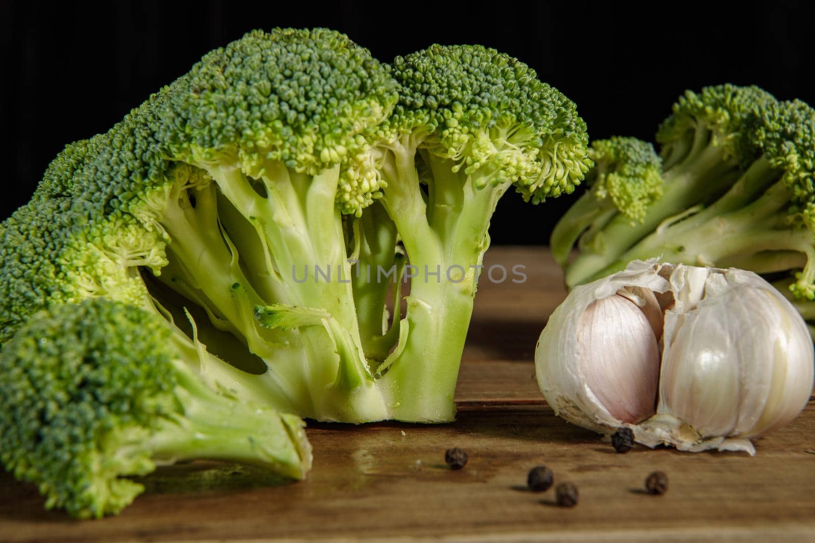Raw green broccoli florets on a wooden board with ingredients. Close-up.