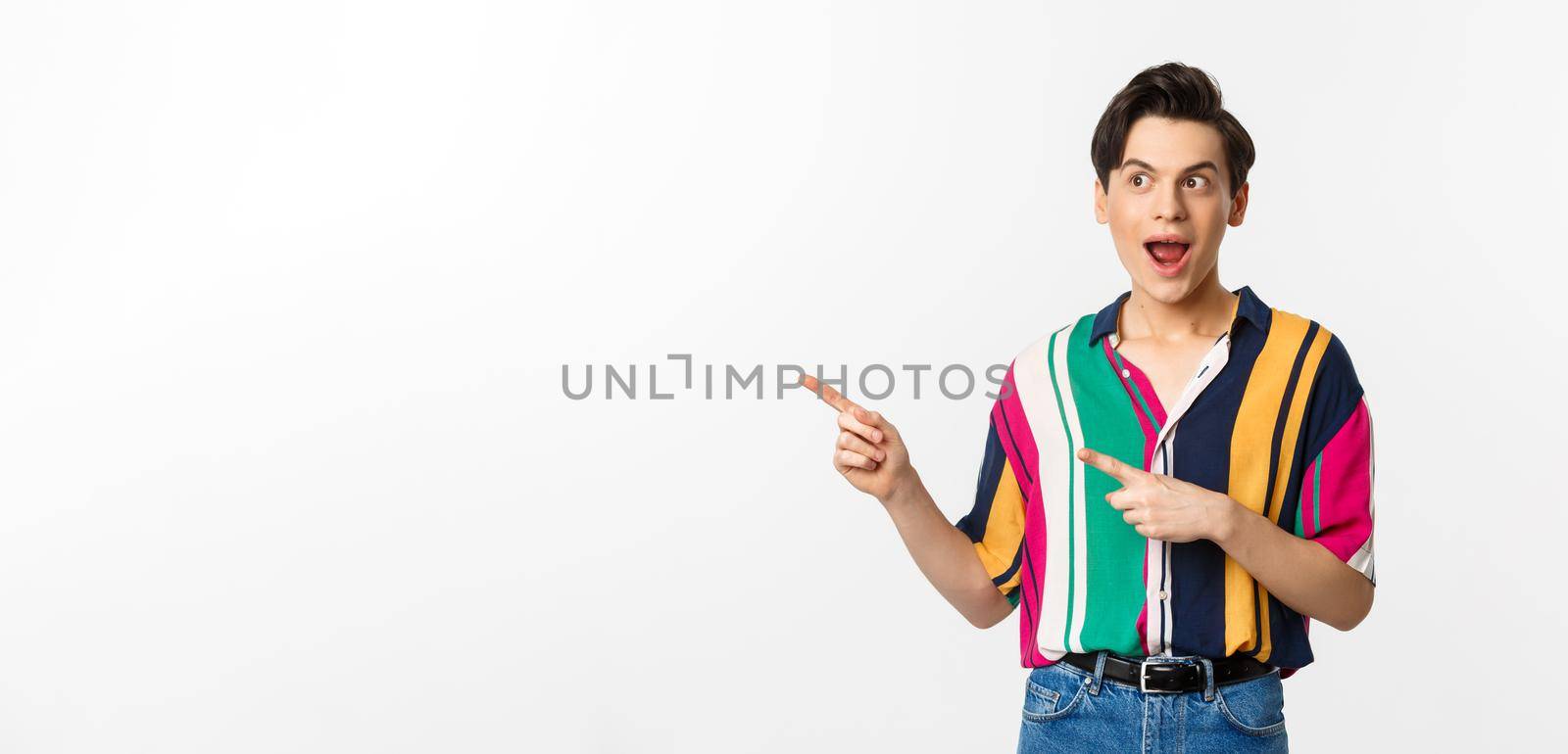 Excited happy man pointing left at promo banner, looking amazed, standing against white background by Benzoix