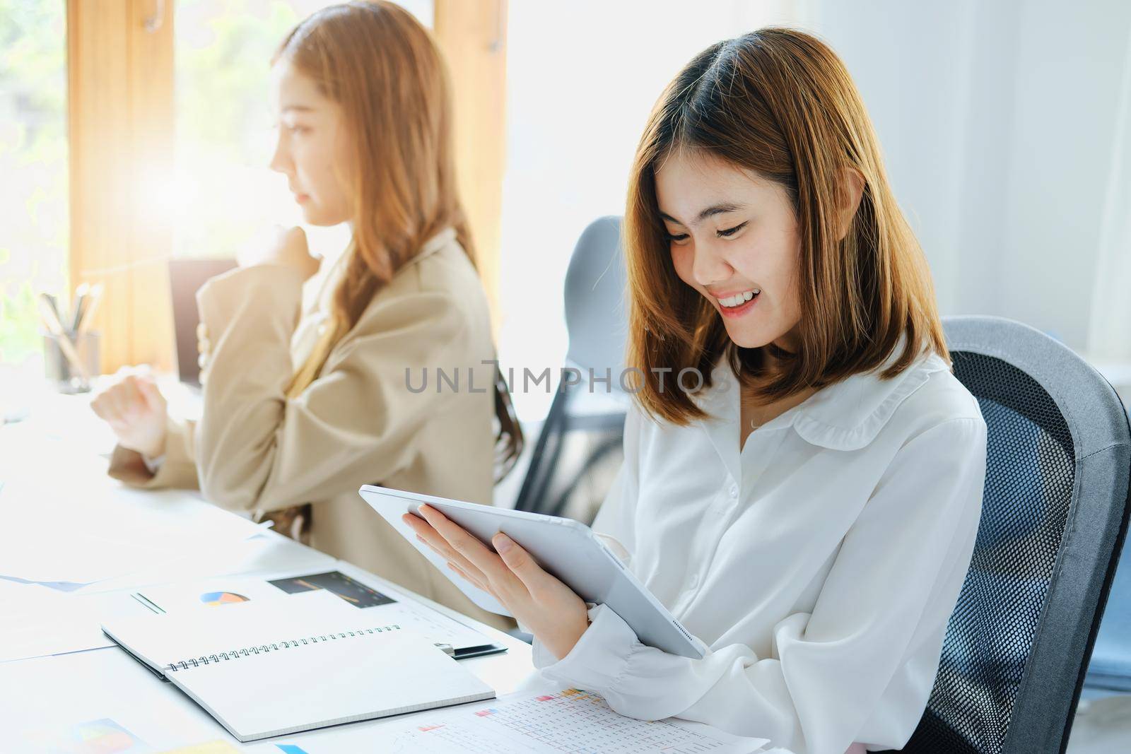 Negotiation, Analysis, Discussion, Portrait of an Asian women economist and marketer using tablet computer to plan investments and financial to prevent risks and losses for the company by Manastrong