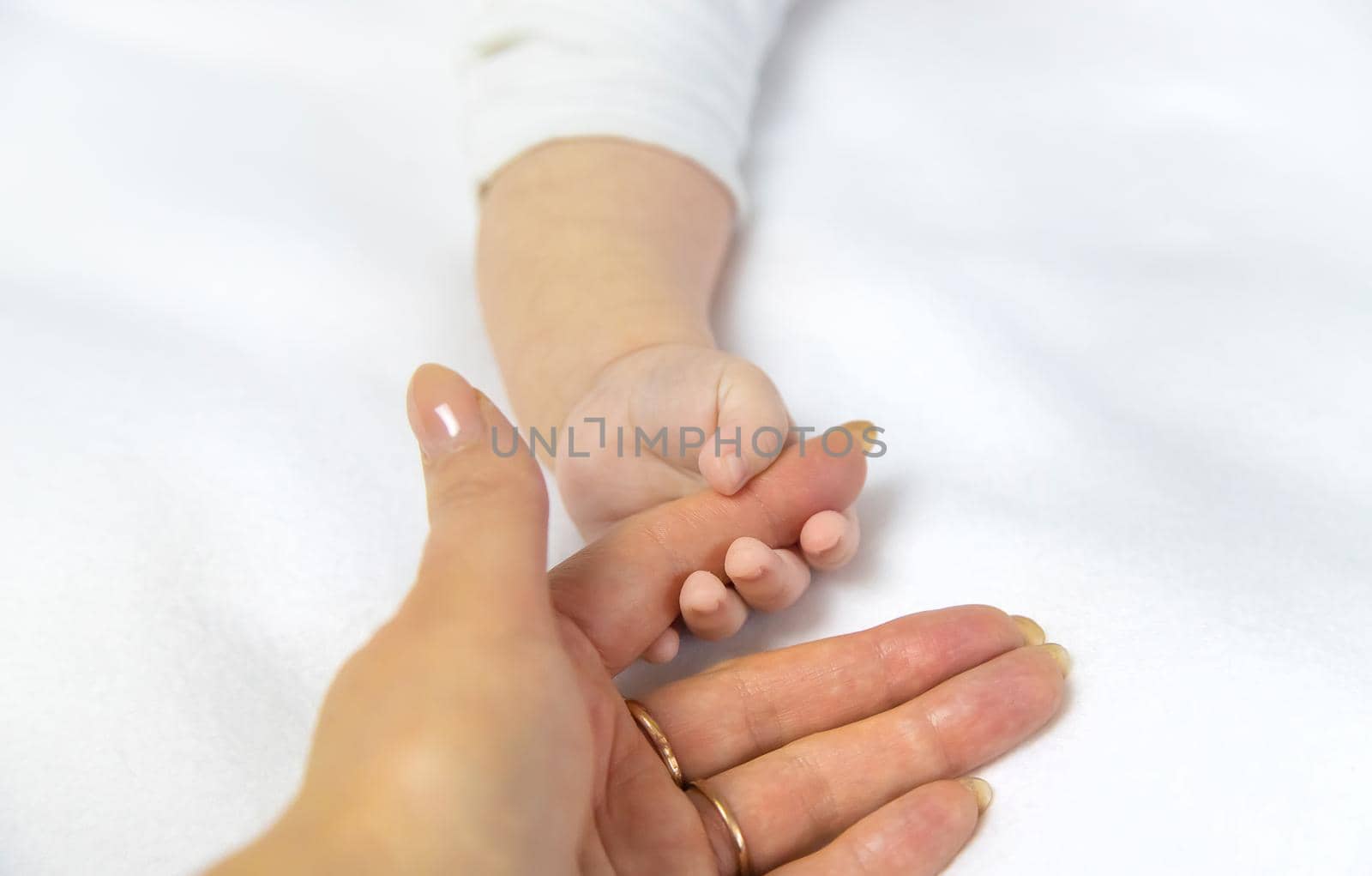 Baby hands with mom's hands against white background. Selective focus. by yanadjana