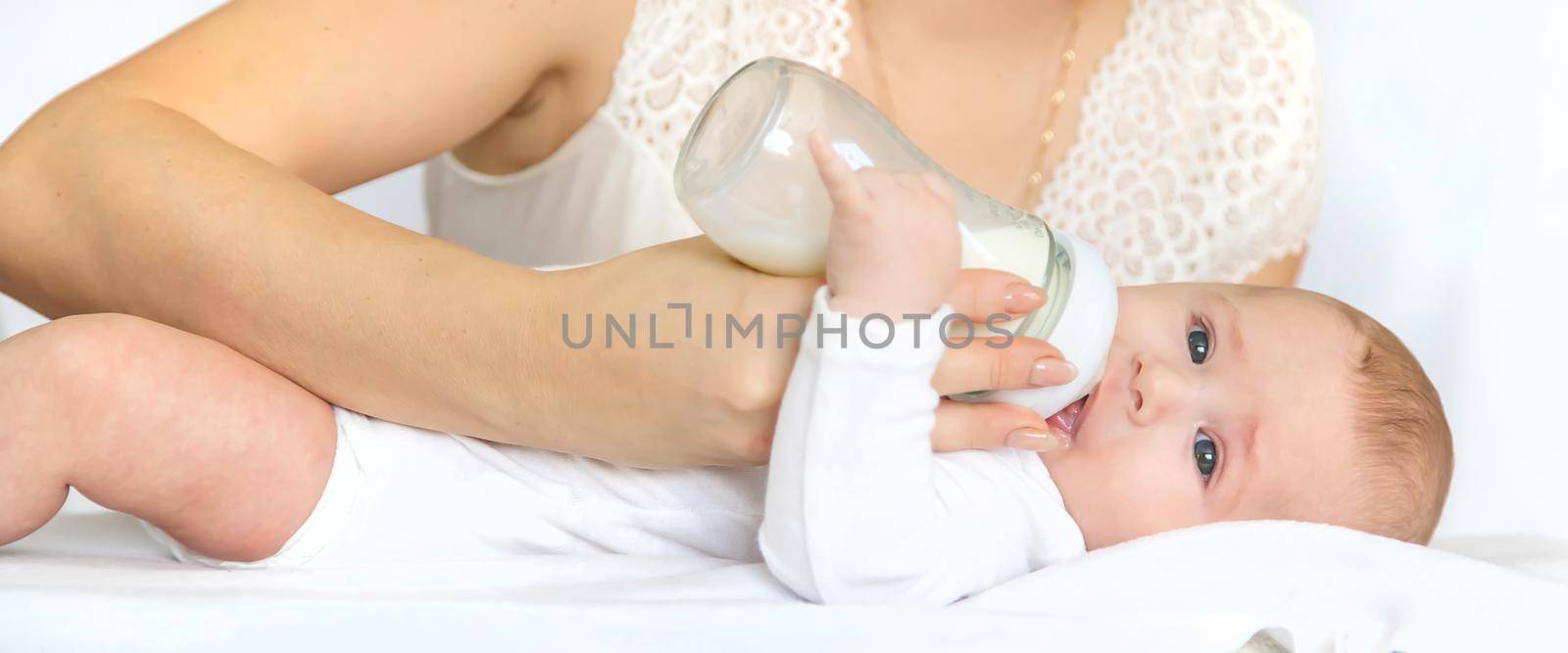 Mother feeds the baby from a bottle. Selective focus. People.