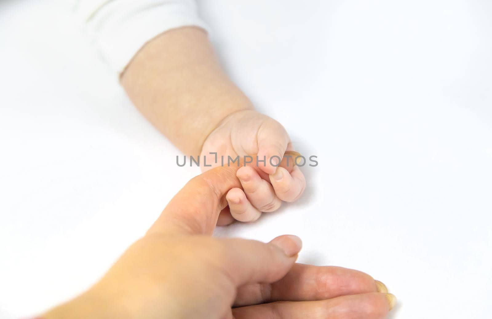 Baby hands with mom's hands against white background. Selective focus. People.