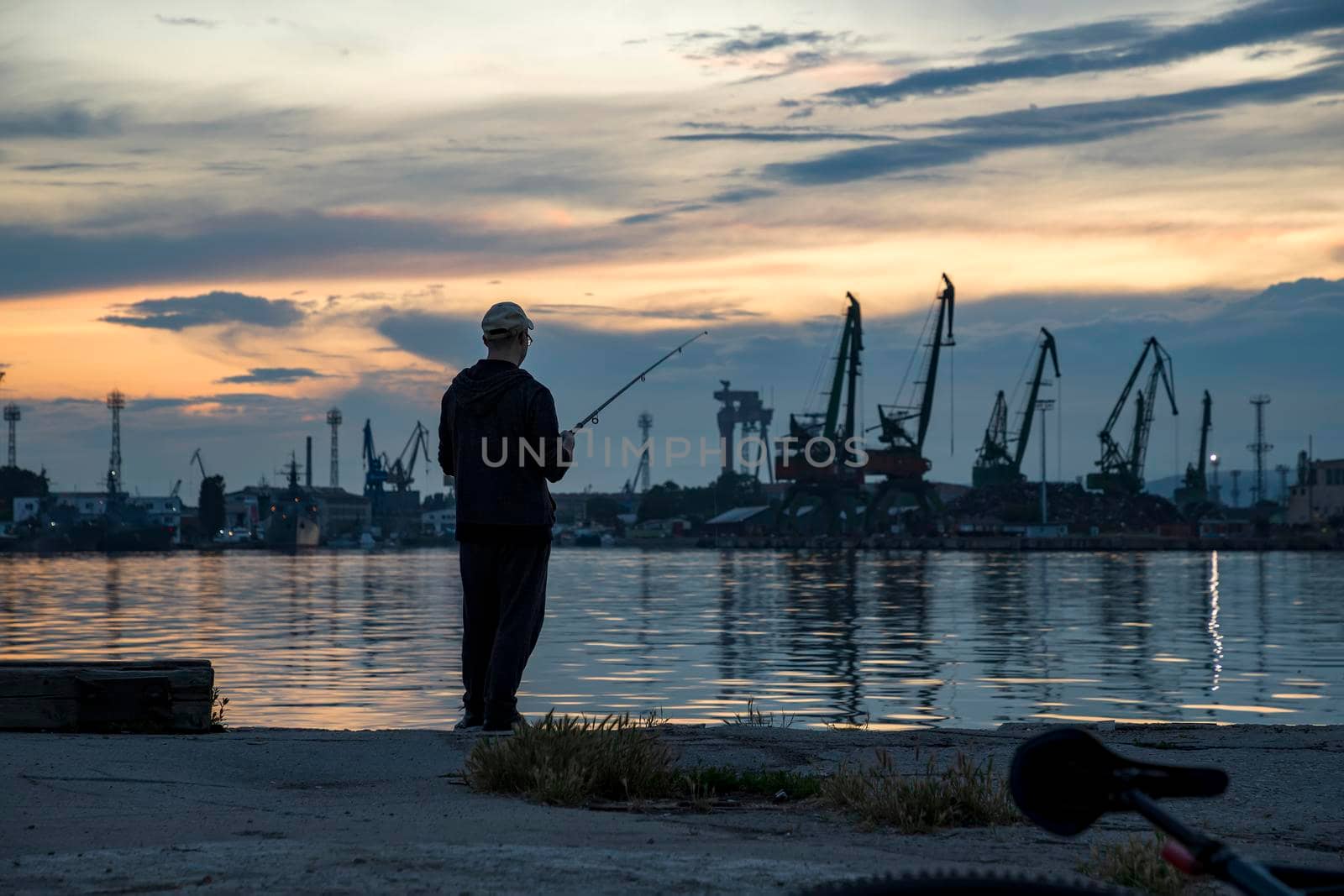 Silhouette of fisherman in the harbor at amazing sunset