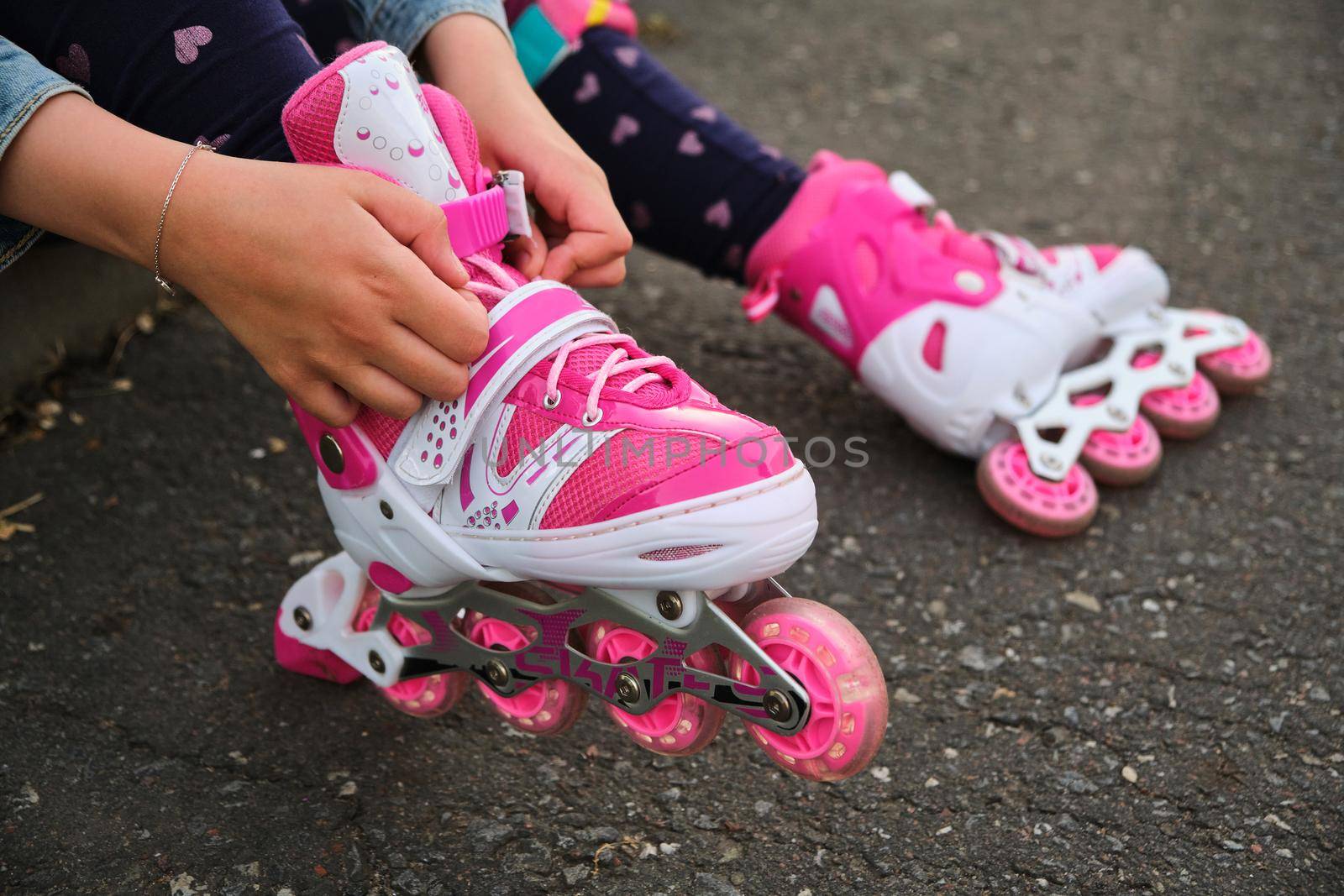 little girl learning to roller skate outdoor. Child enjoying roller skating ride outdoors. Close-up Of Legs Wearing Roller Skating Shoe, Outdoors