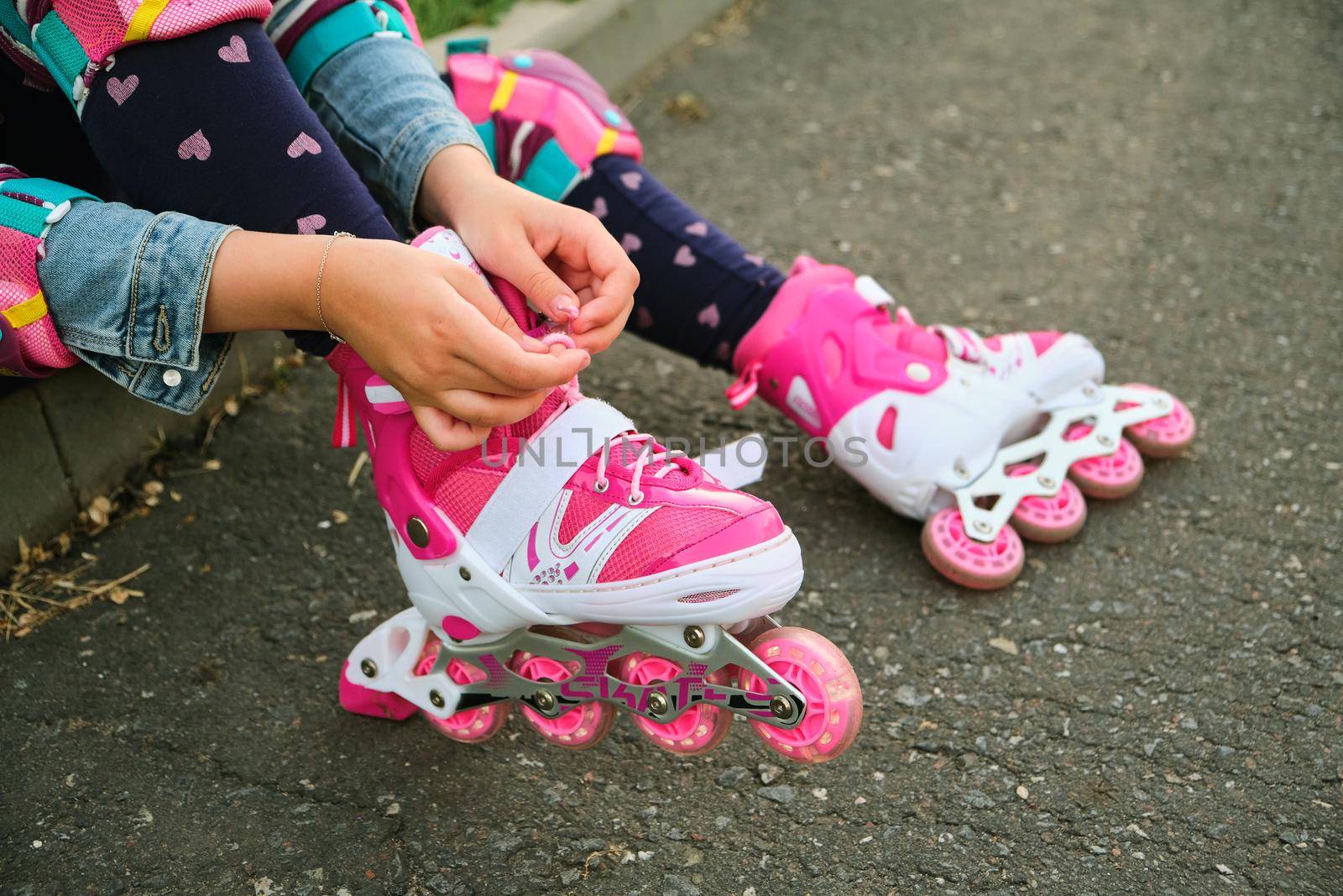 little girl learning to roller skate outdoor. Child enjoying roller skating ride outdoors. Close-up Of Legs Wearing Roller Skating Shoe, Outdoors