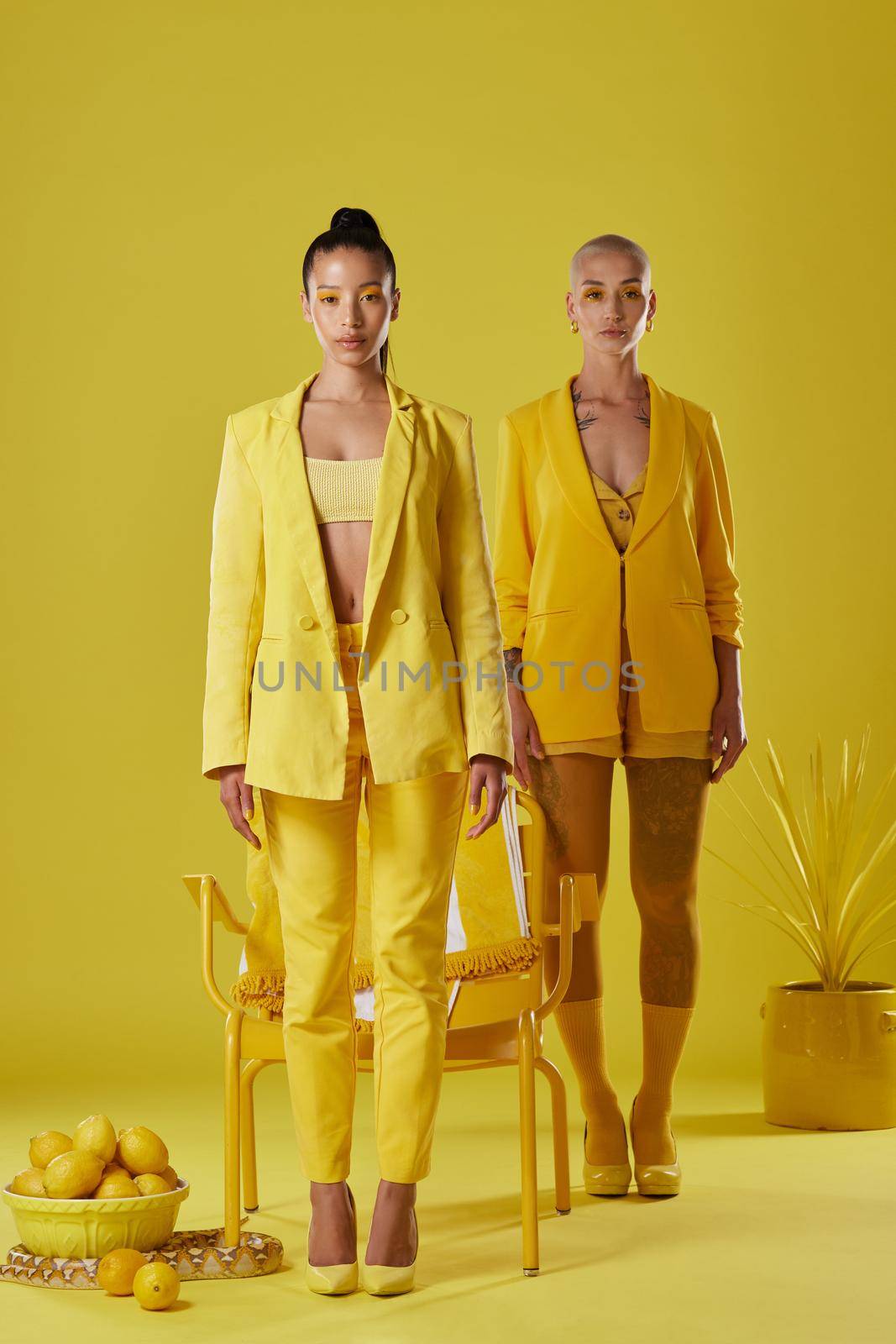 Everything is yellow. Shot of two women dressed in stylish yellow clothes against a yellow background. by YuriArcurs