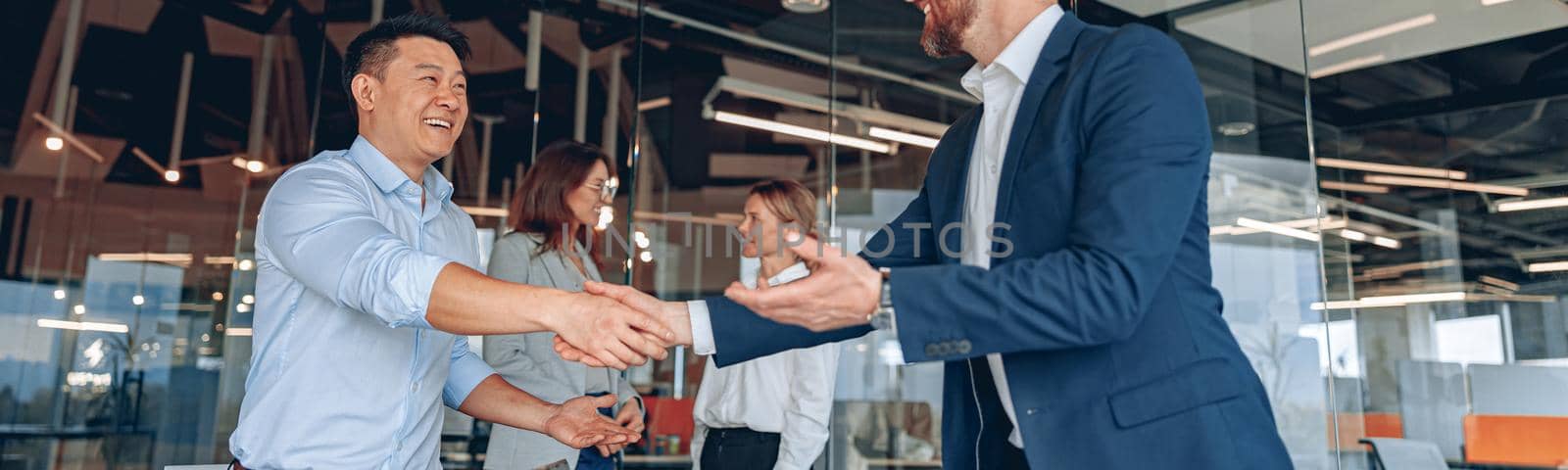 colleagues are shaking their hands in modern office during teamwork meeting by Yaroslav_astakhov