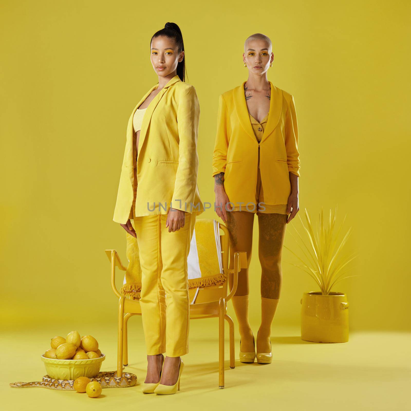 Everyone can pull off the yellow look, just not this good. Shot of two women dressed in stylish yellow clothes against a yellow background. by YuriArcurs