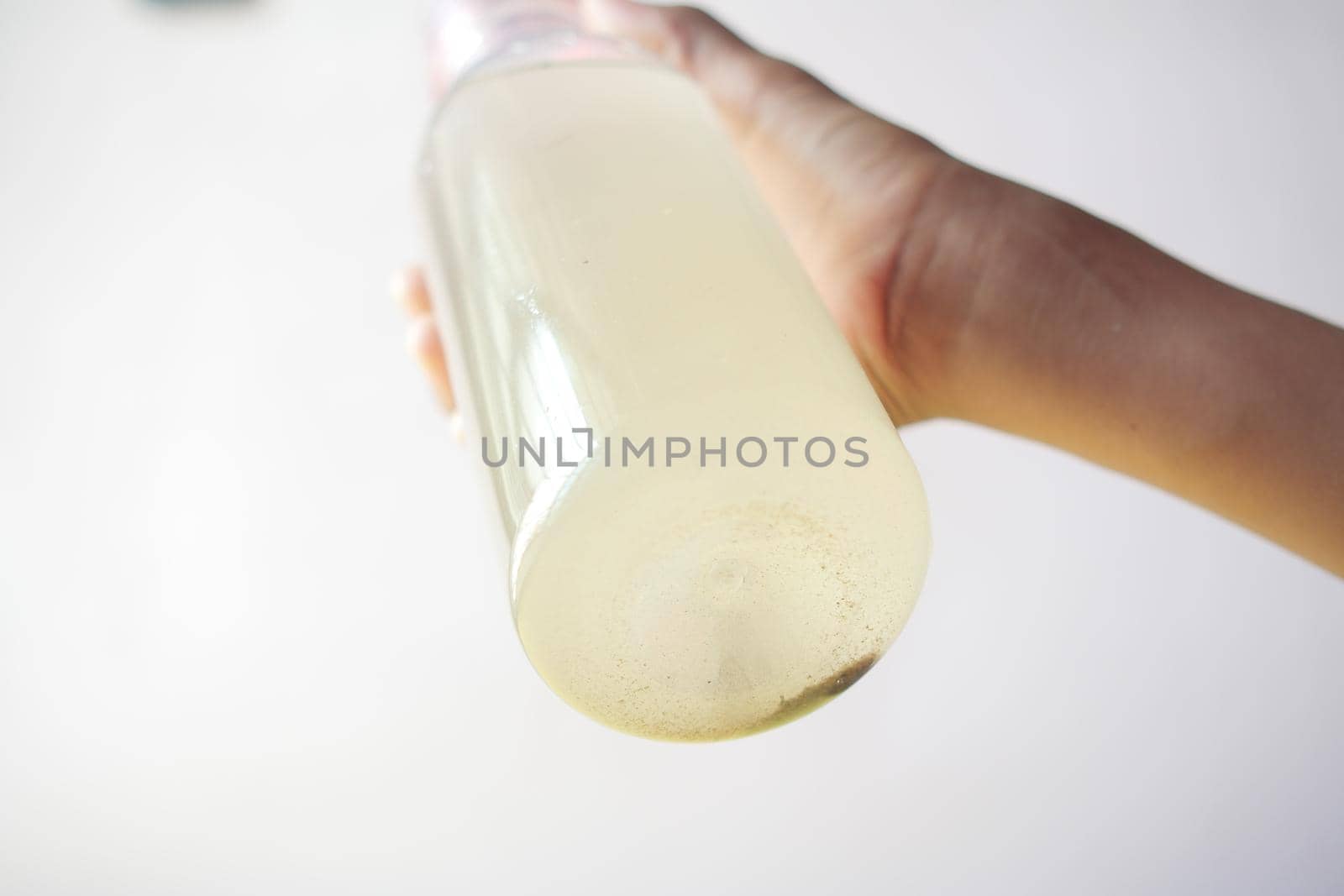holding dirty glass of water against white background .