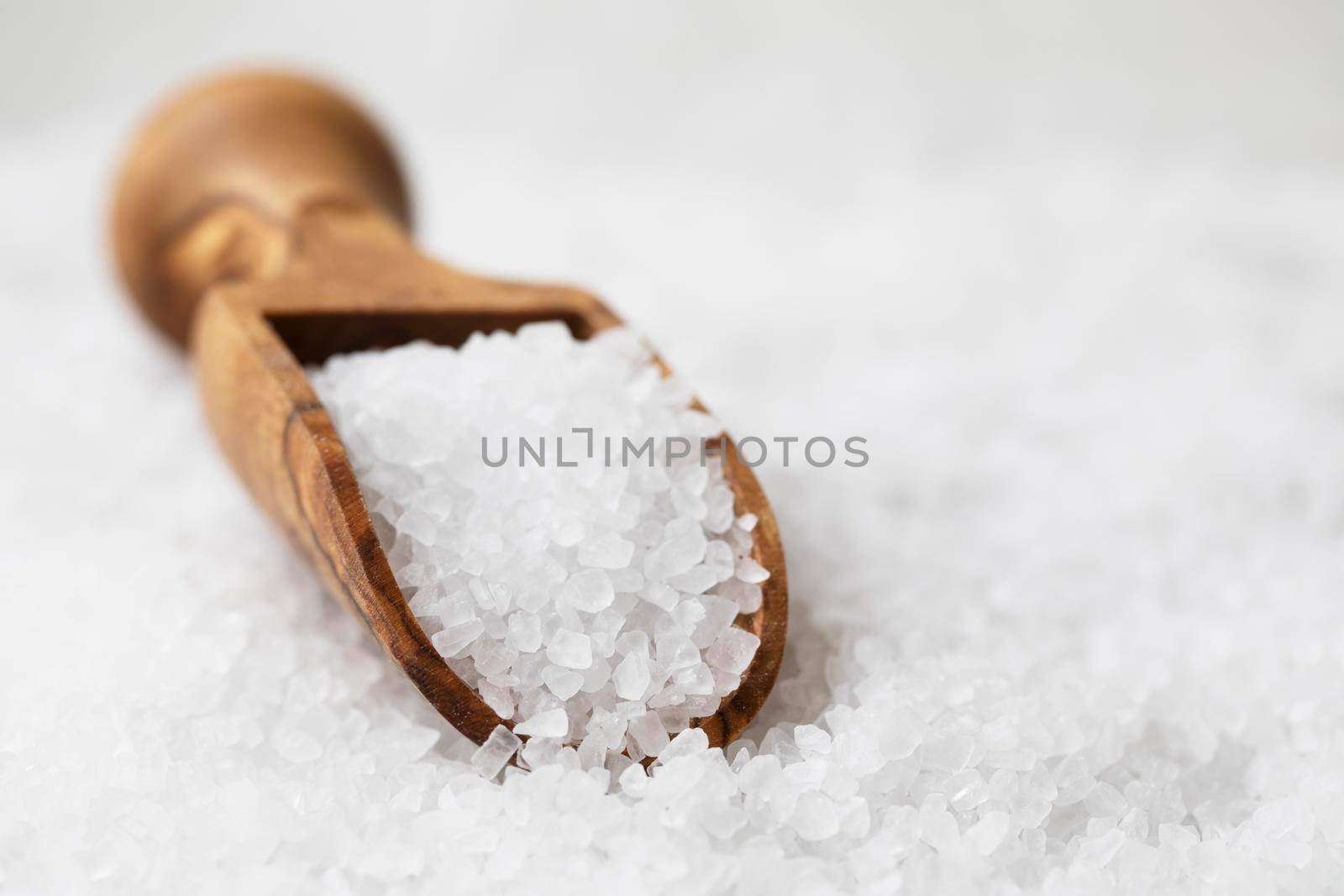 Salt crystals in wooden scoop on bed of salt.
