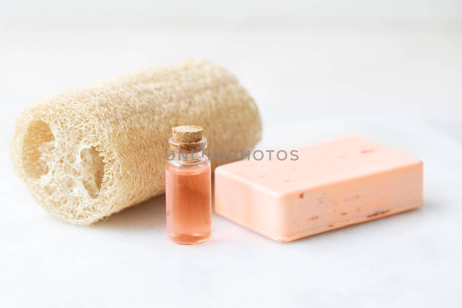 Bar of soap with two small bottles of fruit extracts and loofa sponge.
