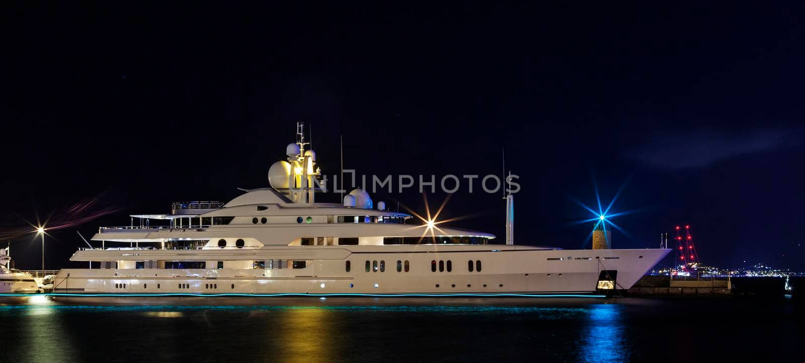 white yacht illuminated by night lights of a port