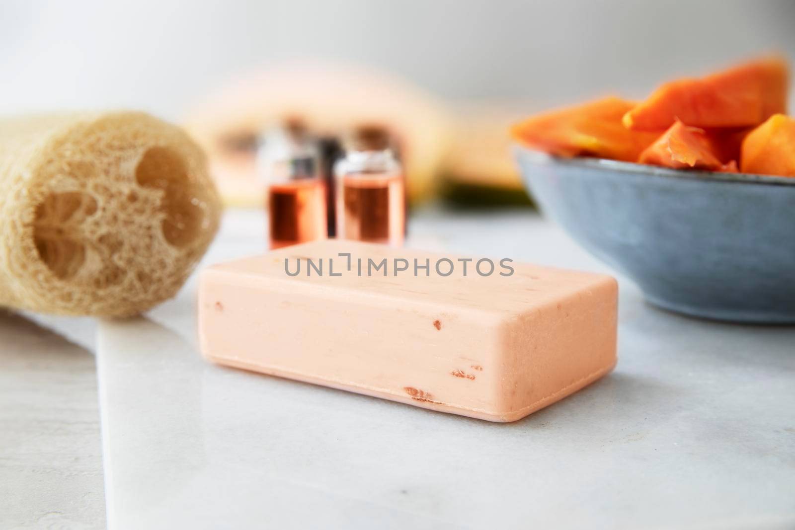 Bar of soap with two small bottles of papaya extracts and loofa sponge.