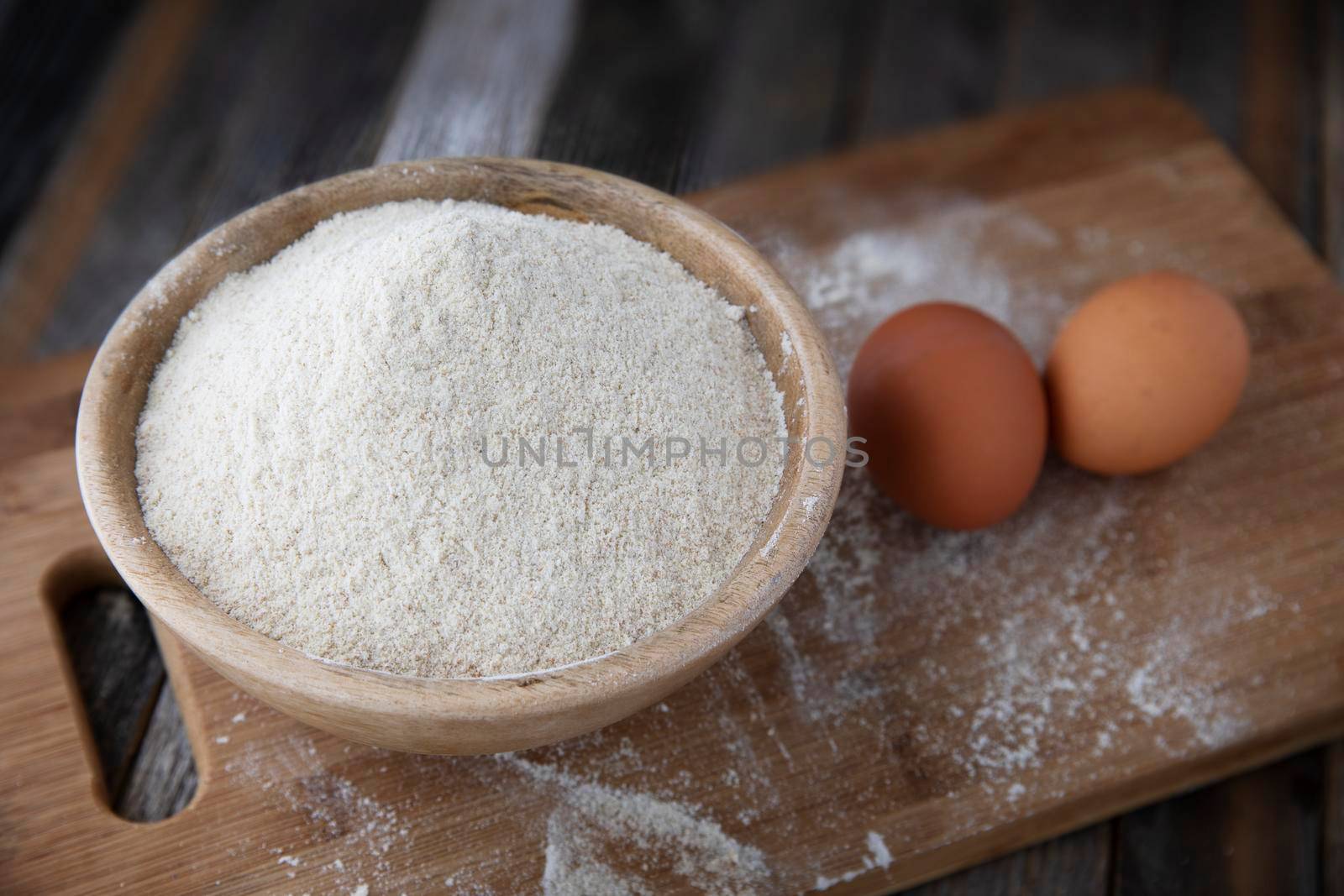 Bowl of whole wheat flour and two eggs on a cutting board.