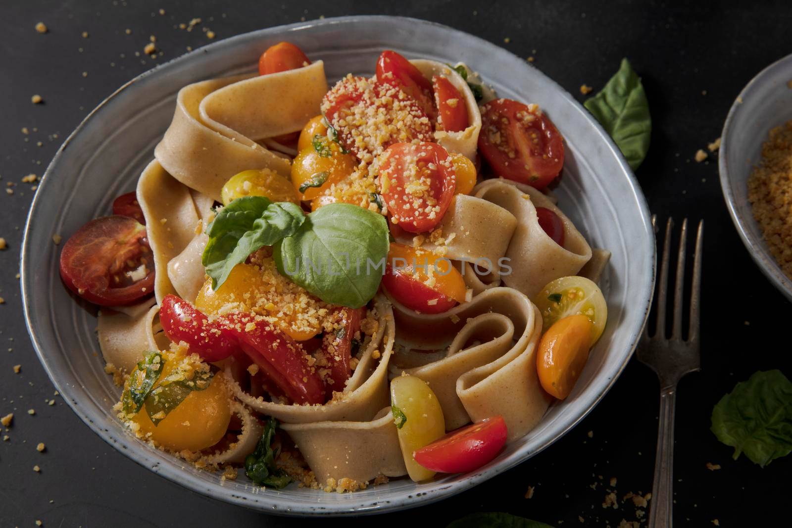 Healthy whole wheat pappardelle pasta with fresh tomatoes and basil, and a vegan nut based topping.