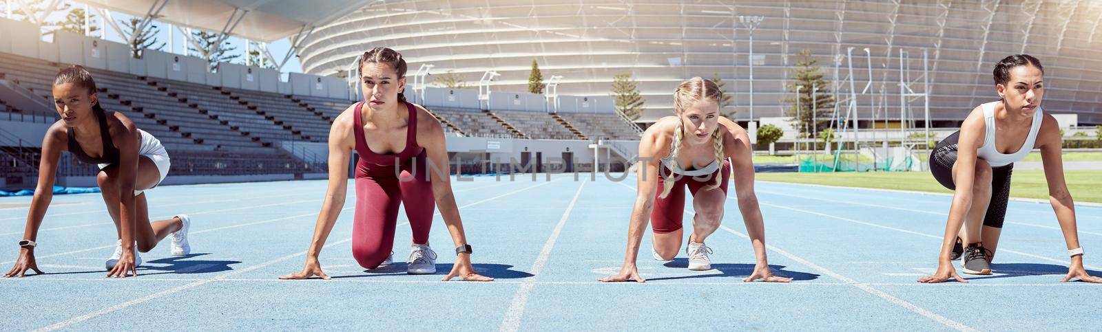Group of determined female athletes in starting position to begin a sprint or running race on a sports track in a stadium. Focused and diverse women ready to compete in track and field olympic event.