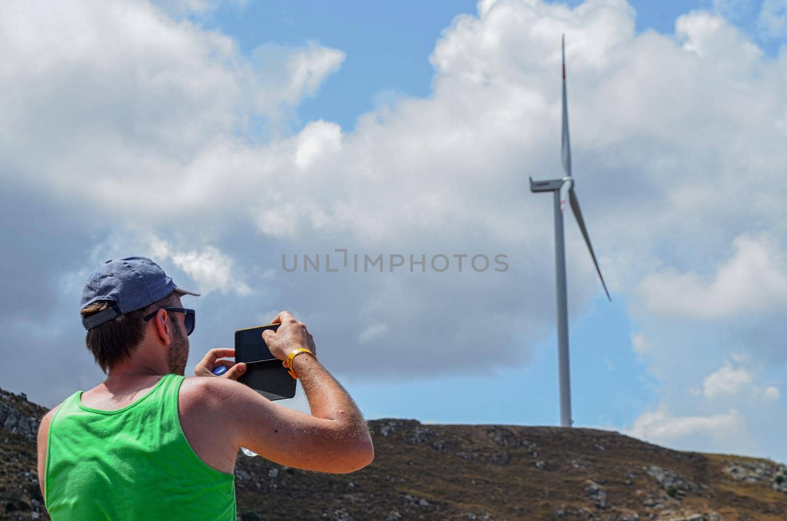 man capture on smartphone a wind turbine on the mountain with clouds by igor010