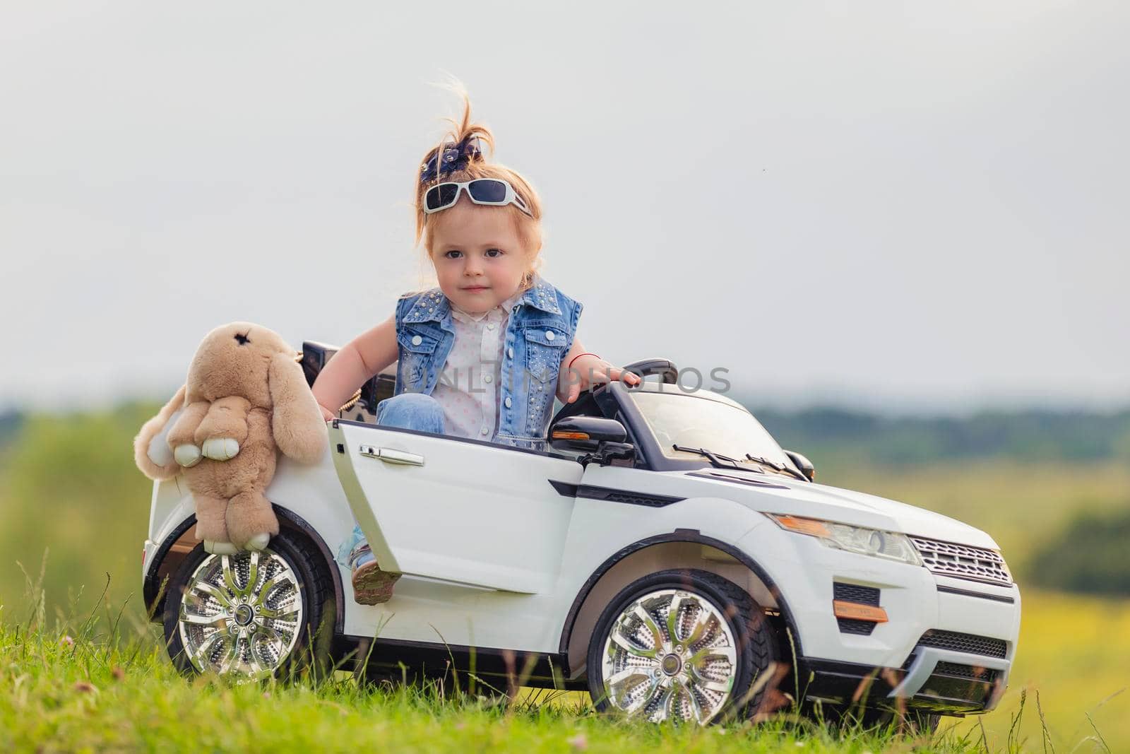 small child stands near his car on the lawn