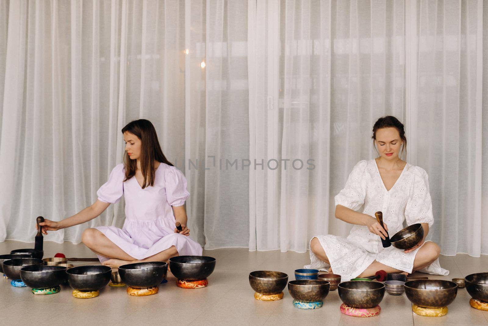 Two female yoga teachers play on Tibetan bowls in the gym during a yoga retreat.