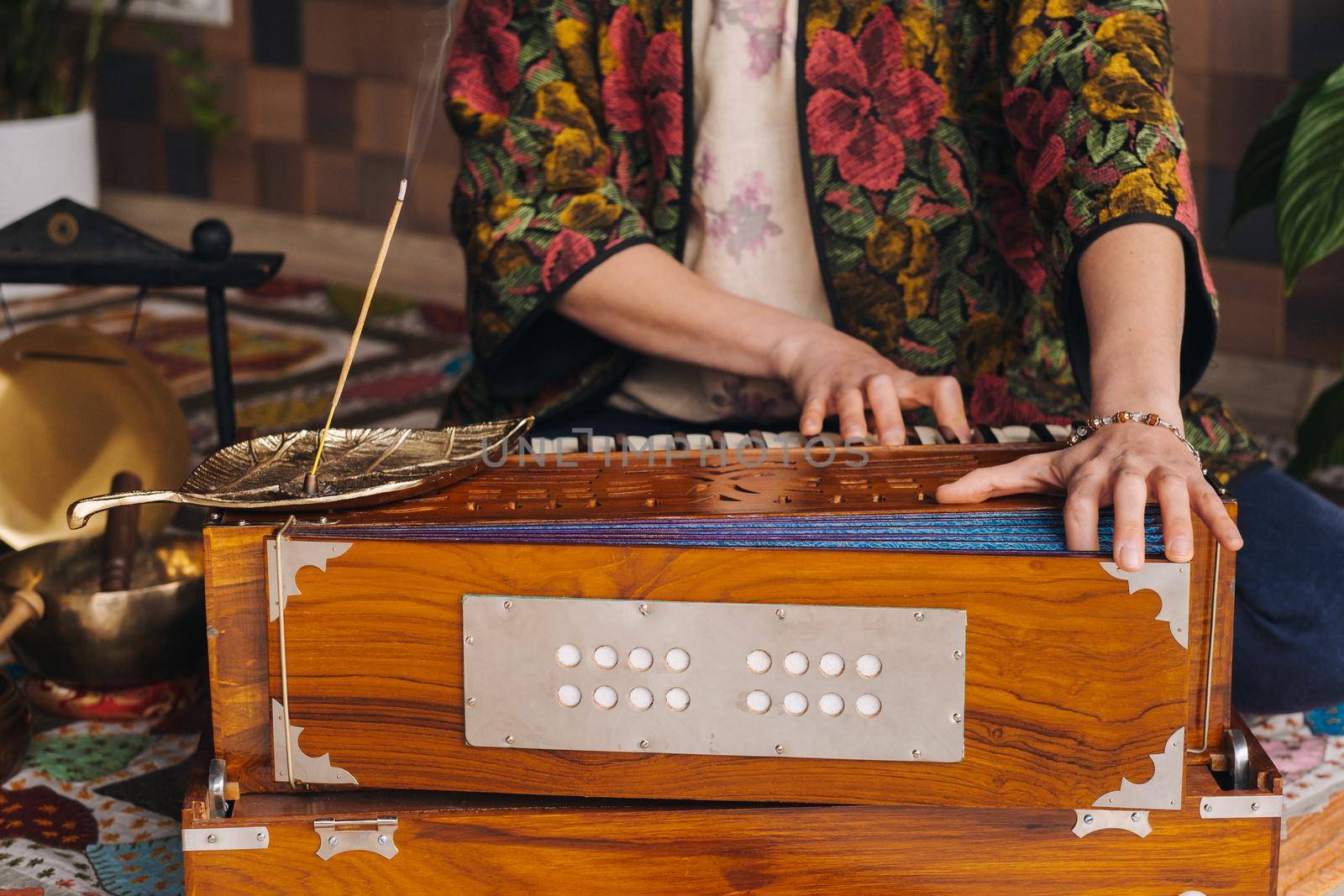 Hands of a woman sitting on the floor and playing the harmonium during the practice of kundalini yoga.