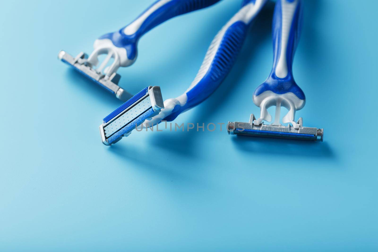 Three shaving machines on a blue background with free space, top view