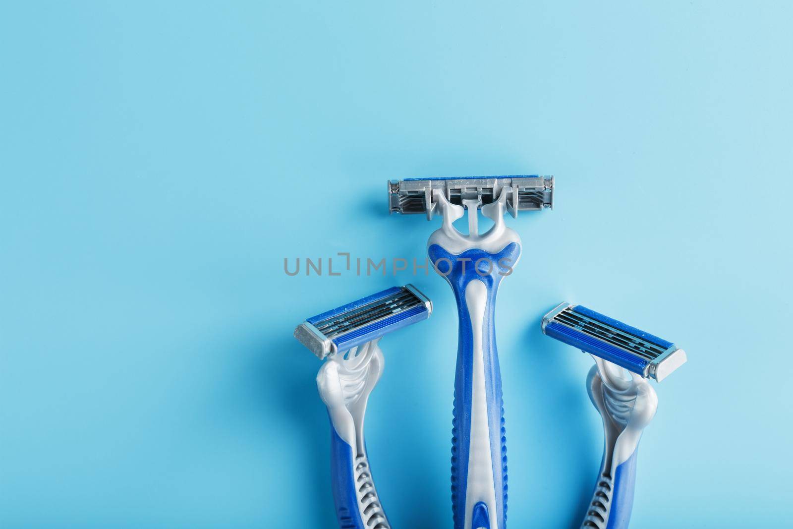 Blue shaving machine with sharp blades on the background of ice cubes close-up. The concept of cleanliness and frosty freshness