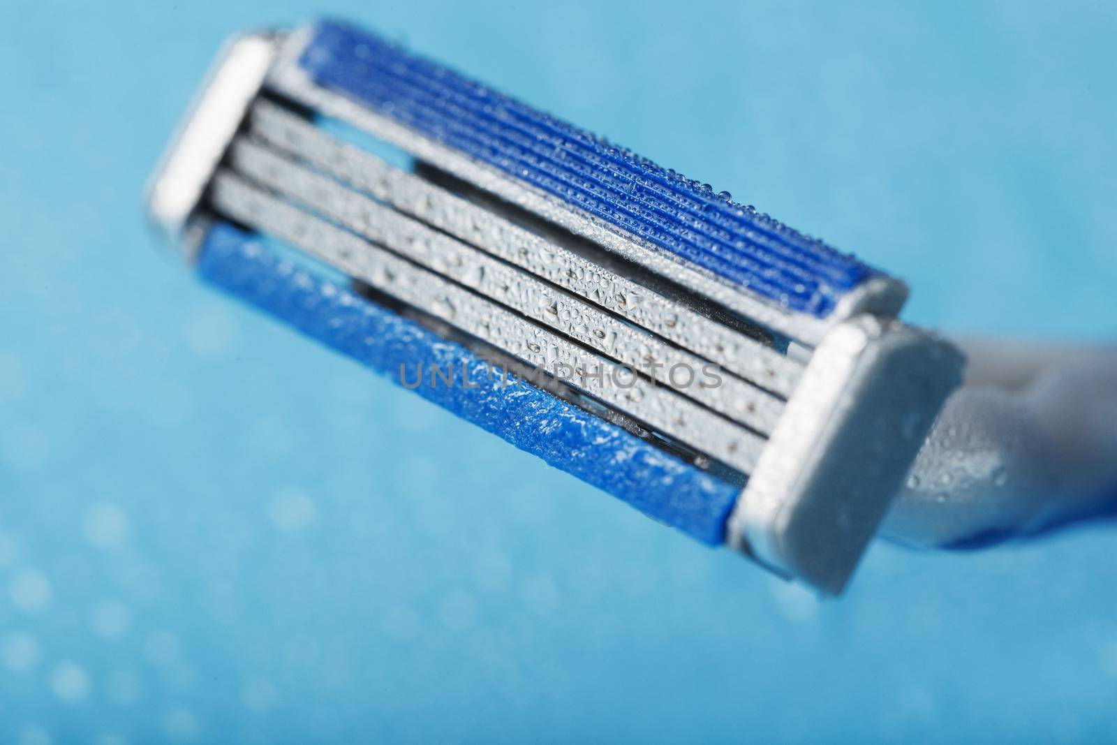 Shaving machine with three blades on a blue background with water drops in close-up by AlexGrec