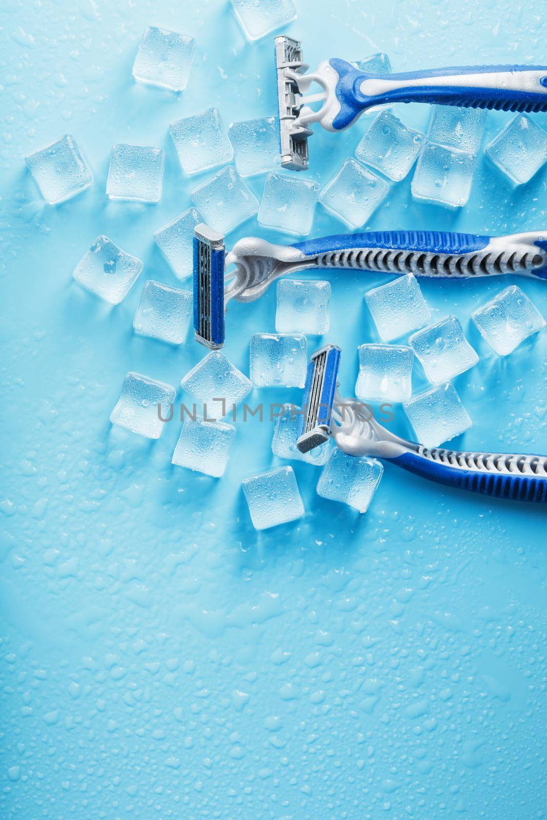 Shaving machine on a blue background with ice cubes. The concept of cleanliness and frosty freshness