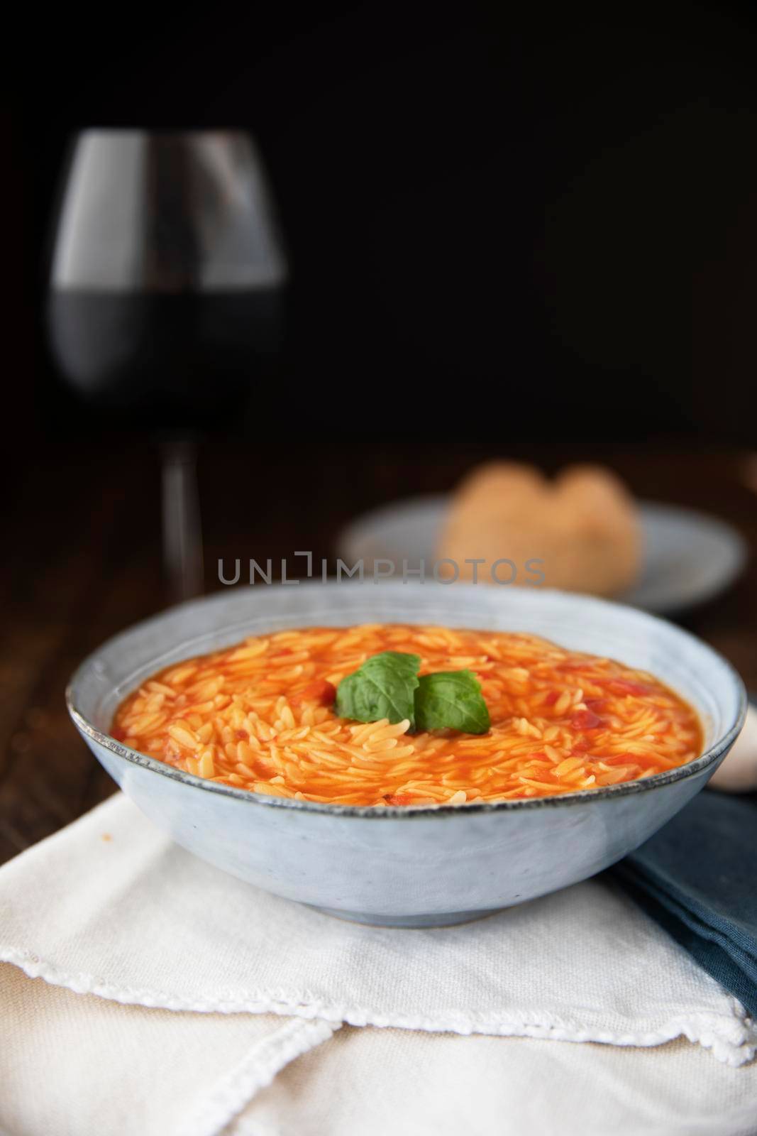 Bowl of orzo pasta and tomato soup with basil