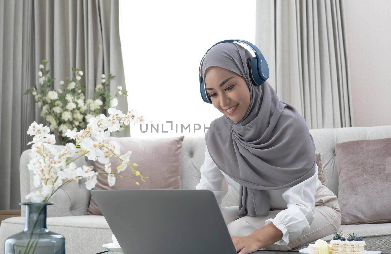 Online Tutoring. Young muslim woman teacher having video call with students, talking at laptop camera, sitting on couch at home.