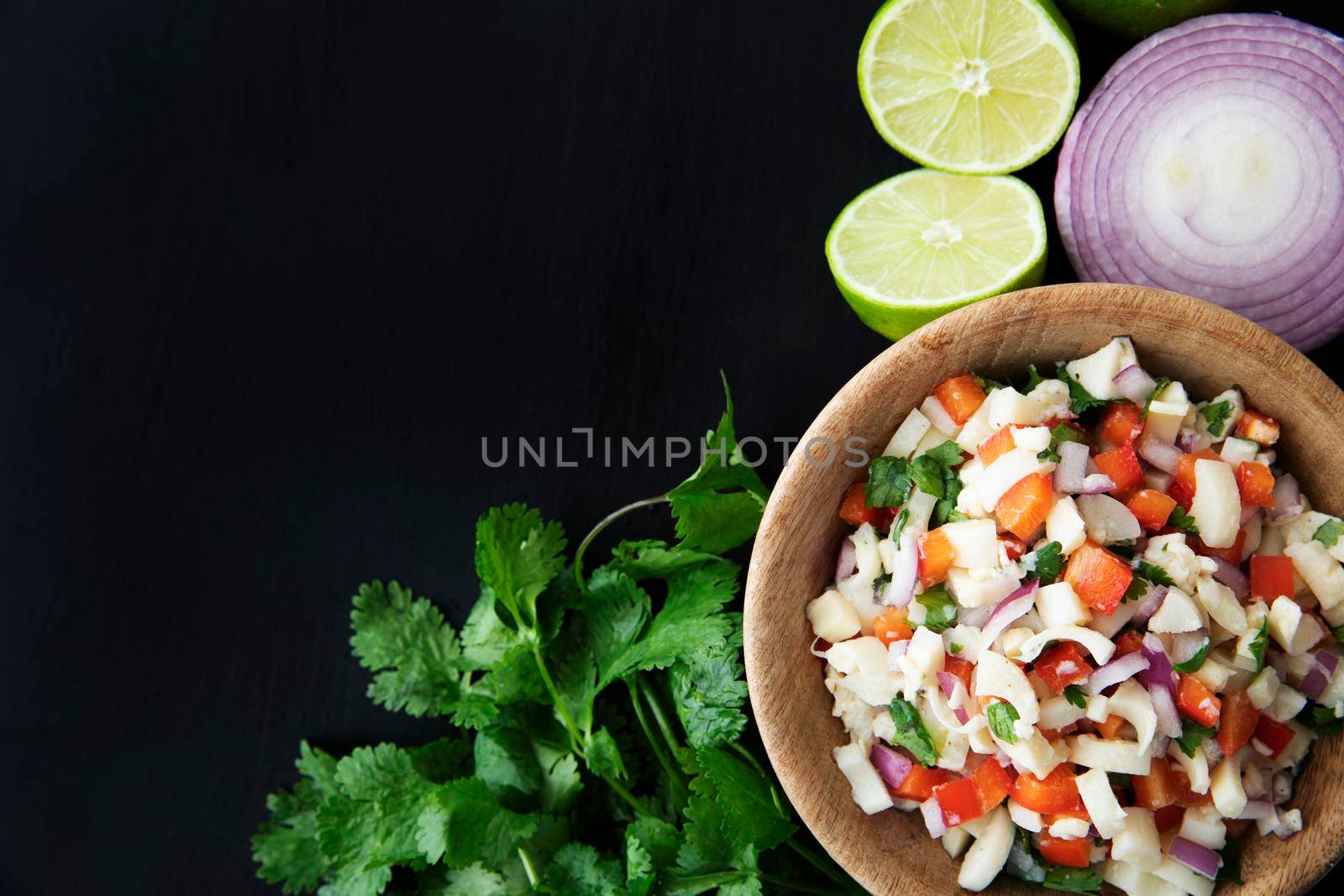 Vegan salad in wooden bowl, with hearts of palm, red onion, pepper, cilantro and lime dressing. Flat lay with copy space.