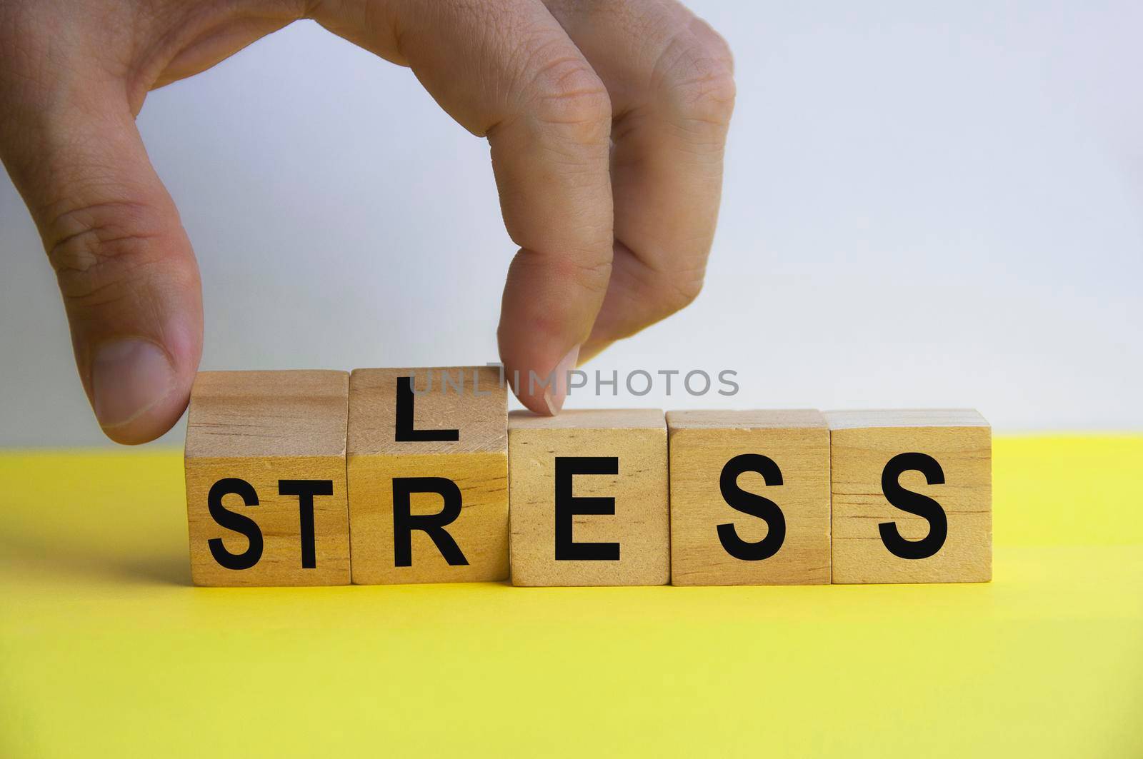 Hand holding wooden cube with word LESS and STRESS. Copy space. Business stress concept.